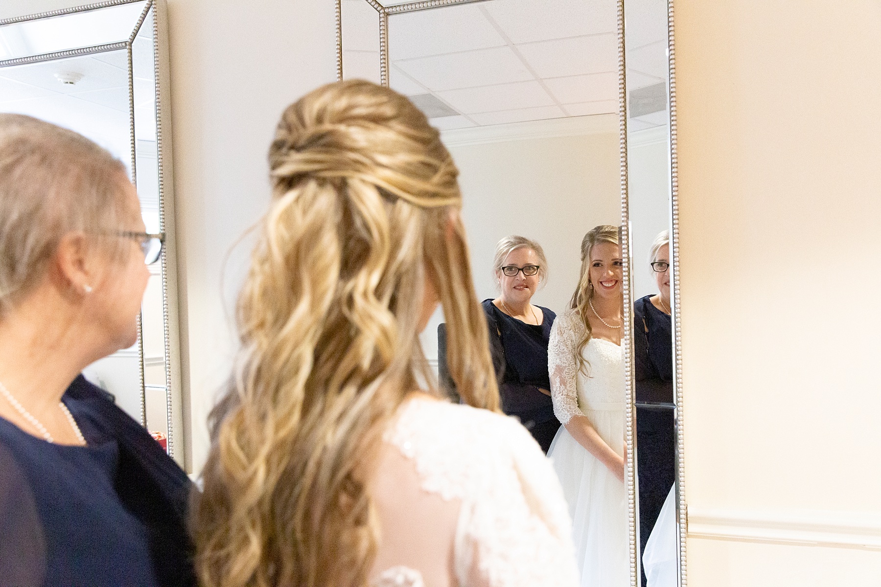 bride looks at reflection in the mirror with mother photographed by Randi Michelle