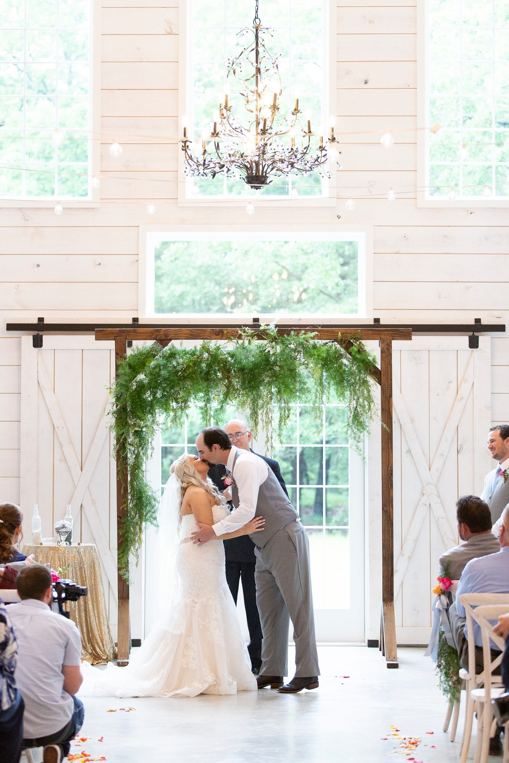 first kiss as husband and wife under greenery on wooden arch photographed by Randi Michelle Weddings