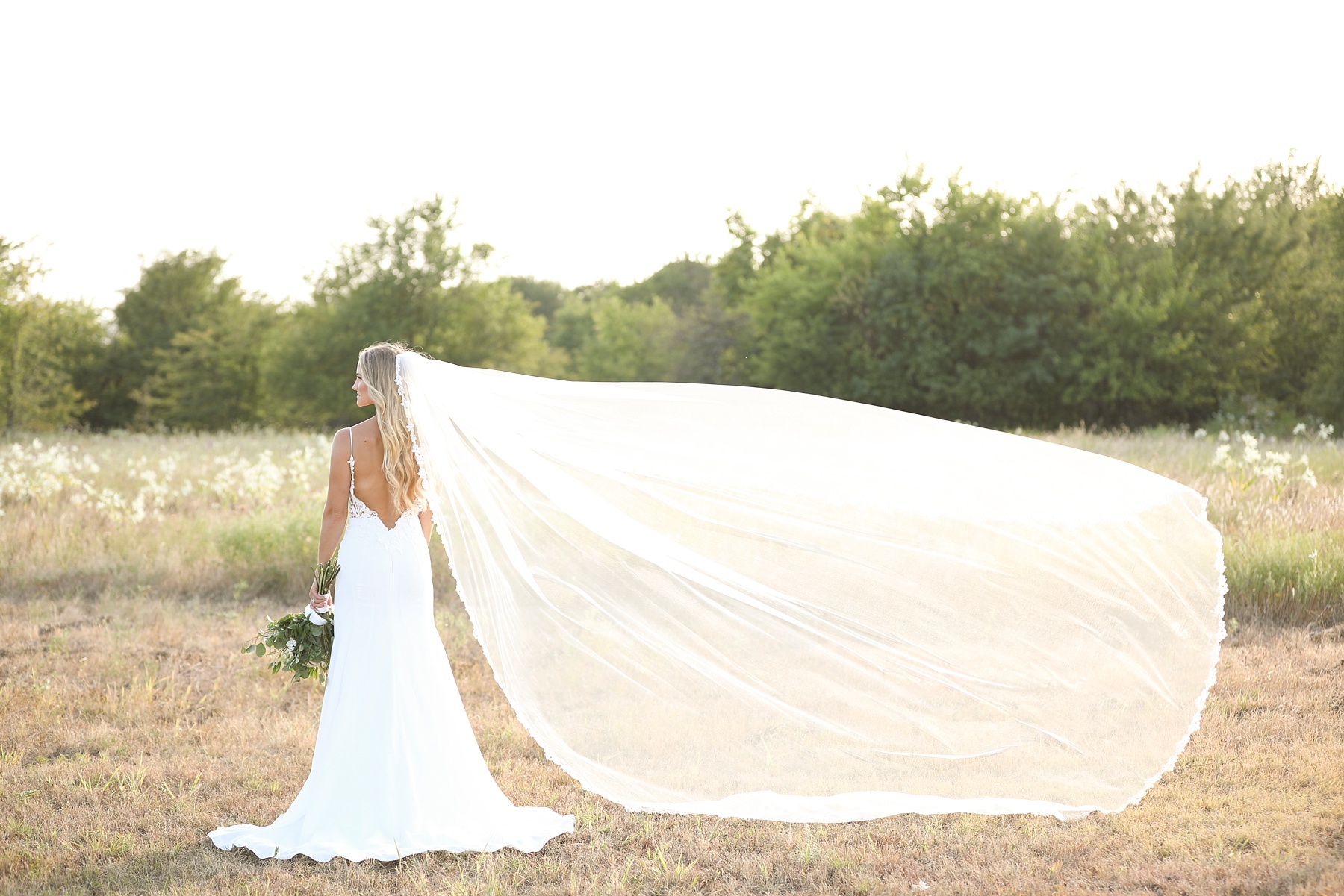 bride stands with veil floating in the air photographed by Randi Michelle
