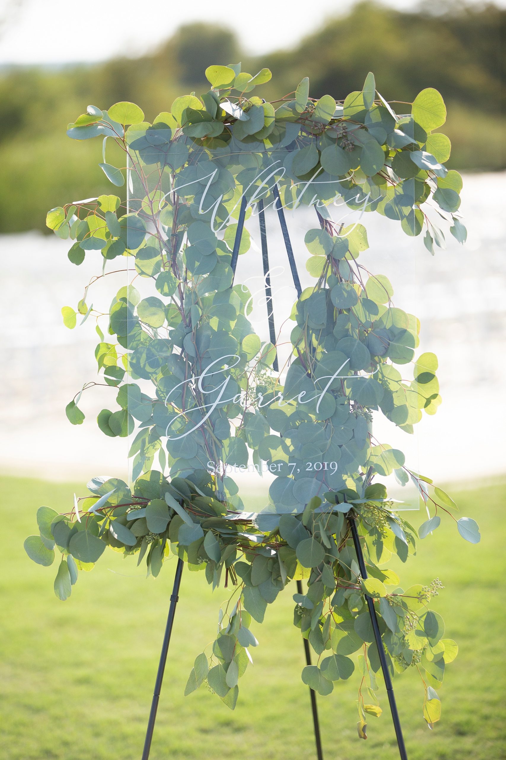 greenery covered clear sign at Texas ceremony photographed by Randi Michelle
