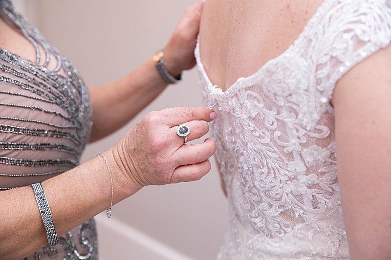 mother of the bride helps bride with gown