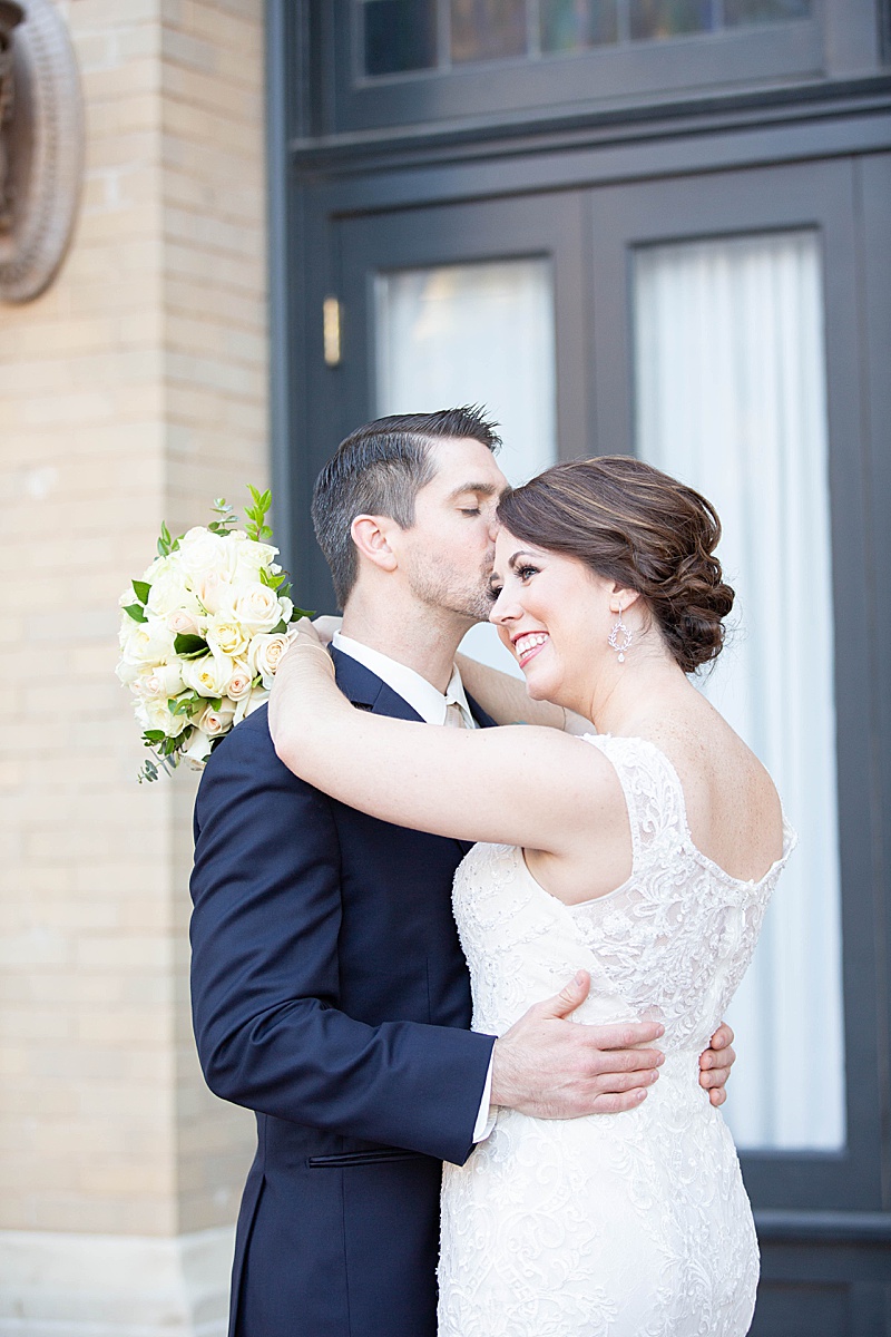 groom kisses bride on forehead during wedding portraits with Randi Michelle