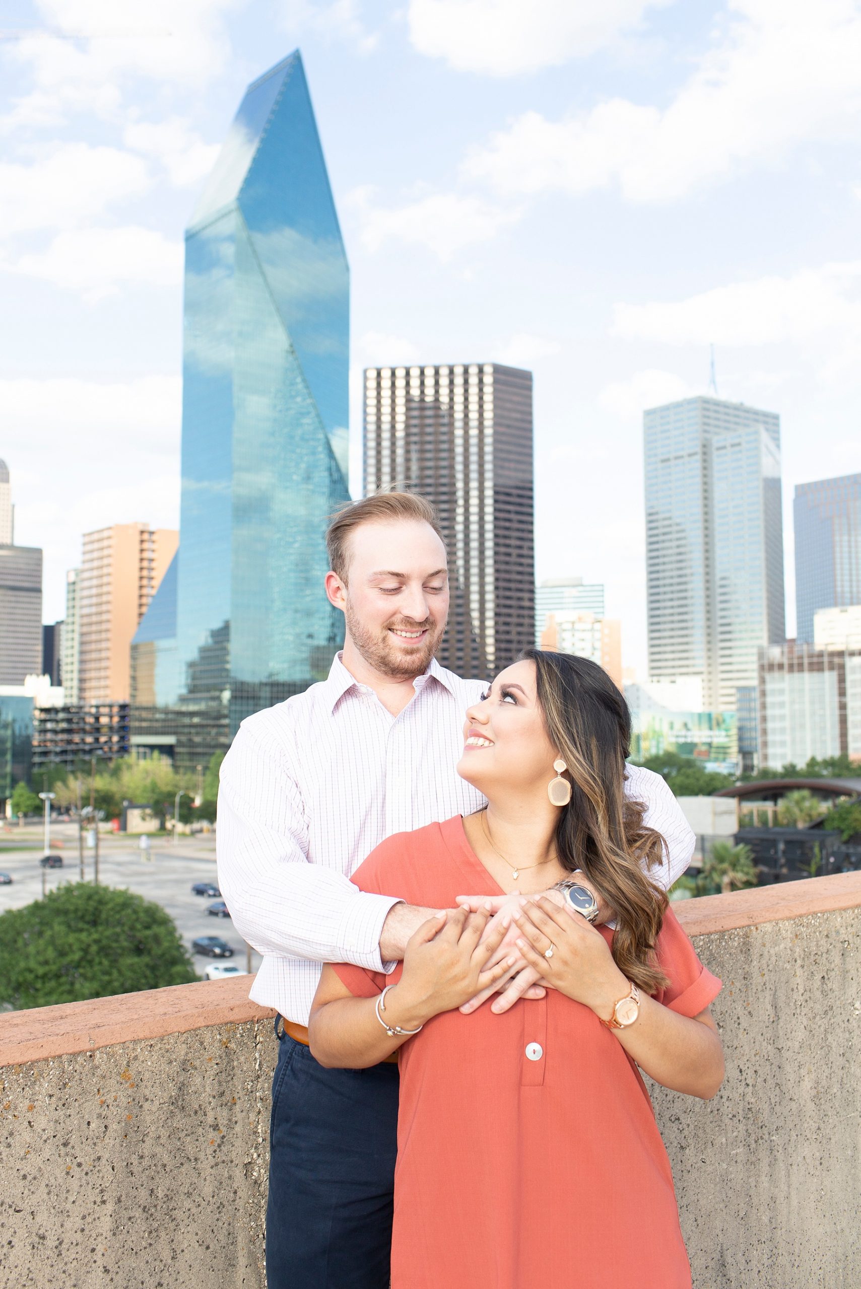 bride and groom embrace on parking garage with Dallas Skyline in background