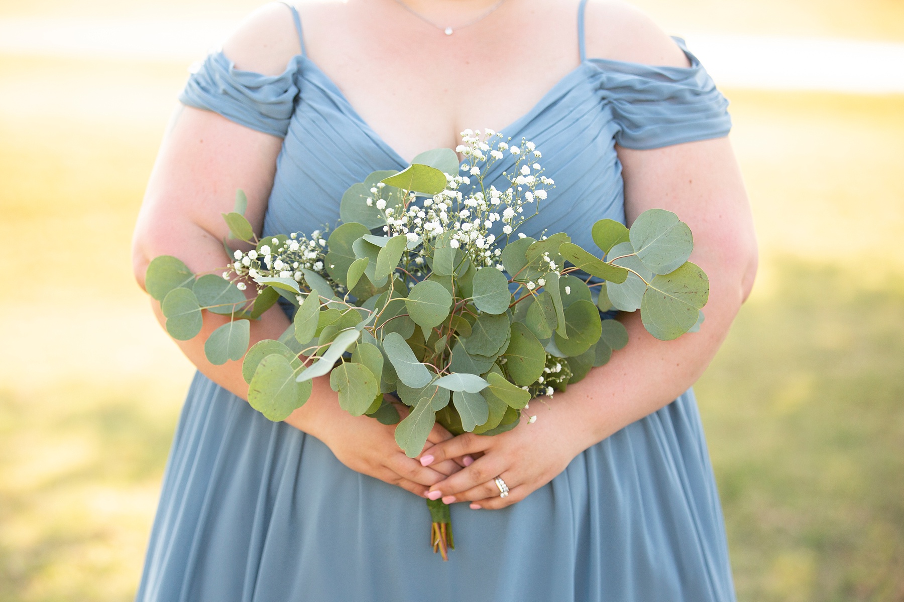 bridesmaid in blue gown holds bouquet of eucalyptus