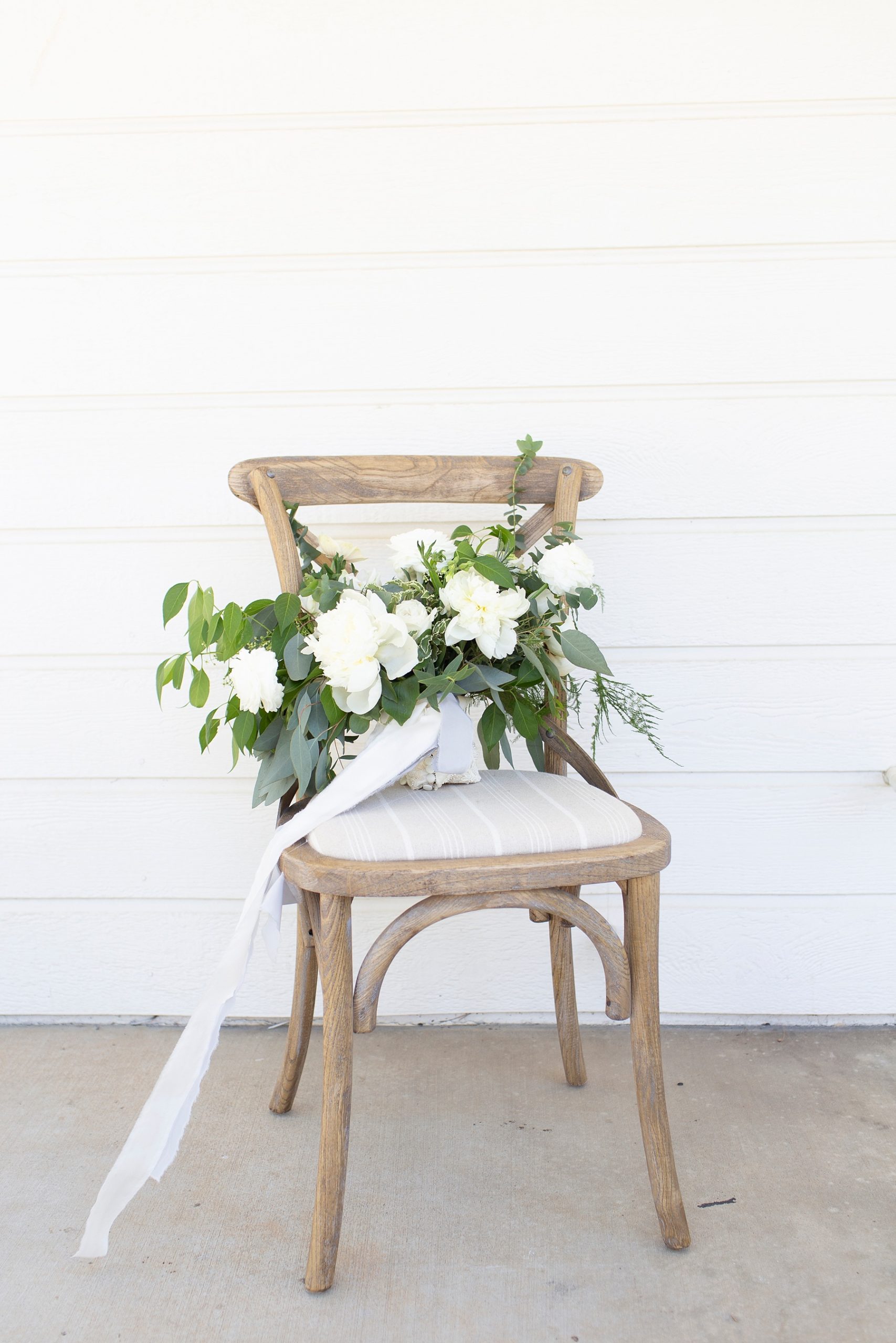 bride's white and green bouquet on chair outside Providence Plateau