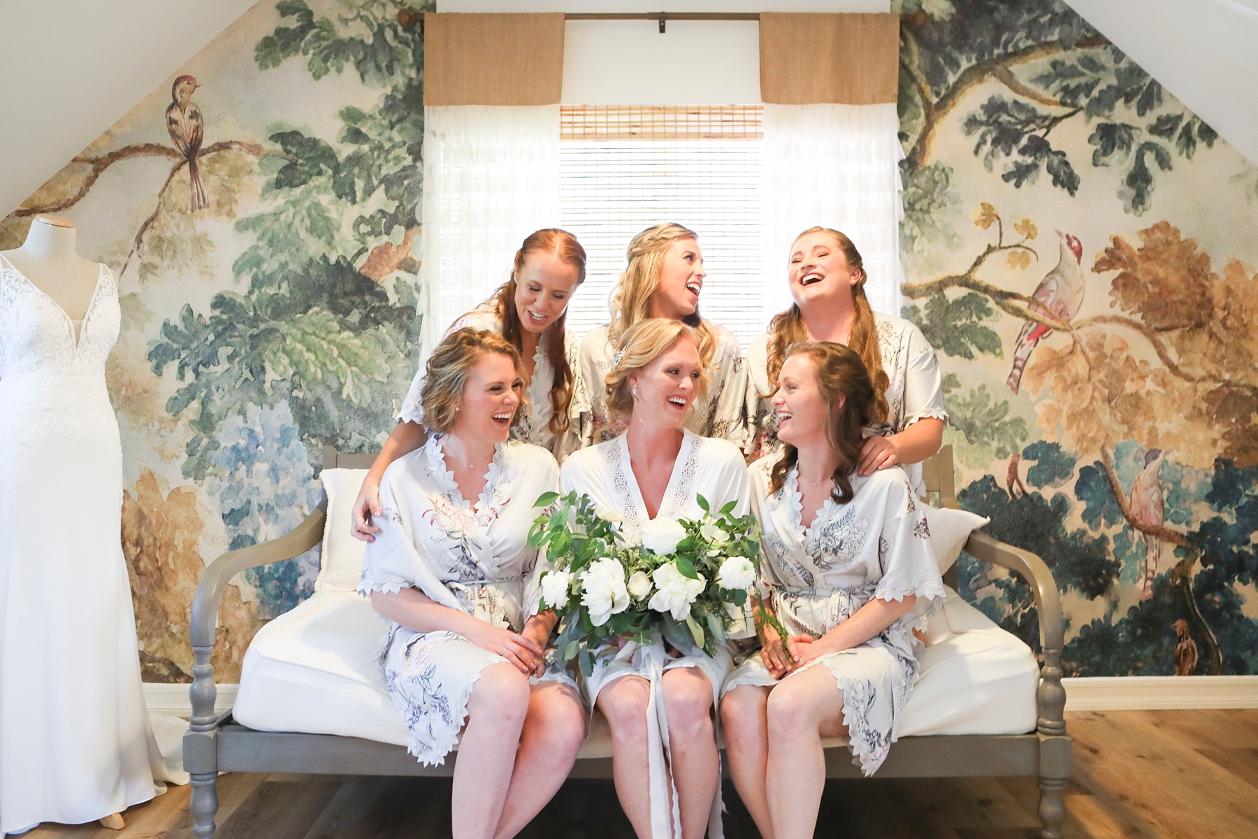 bride laughs with bridesmaids during wedding prep
