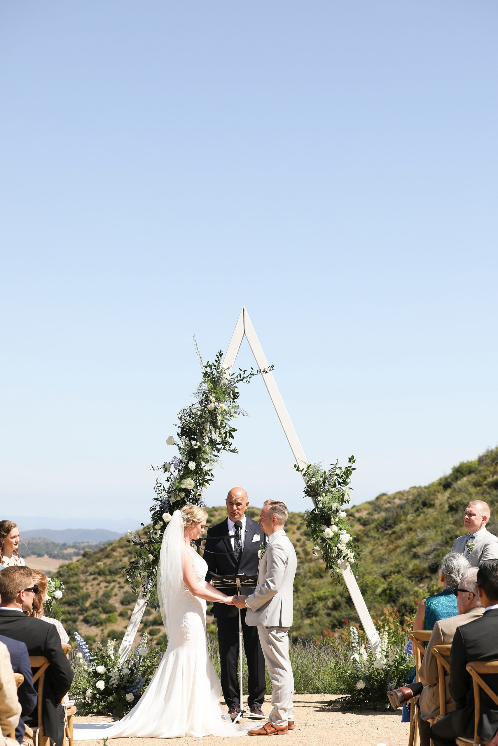 bride and groom exchange vows in front of triangle arbor