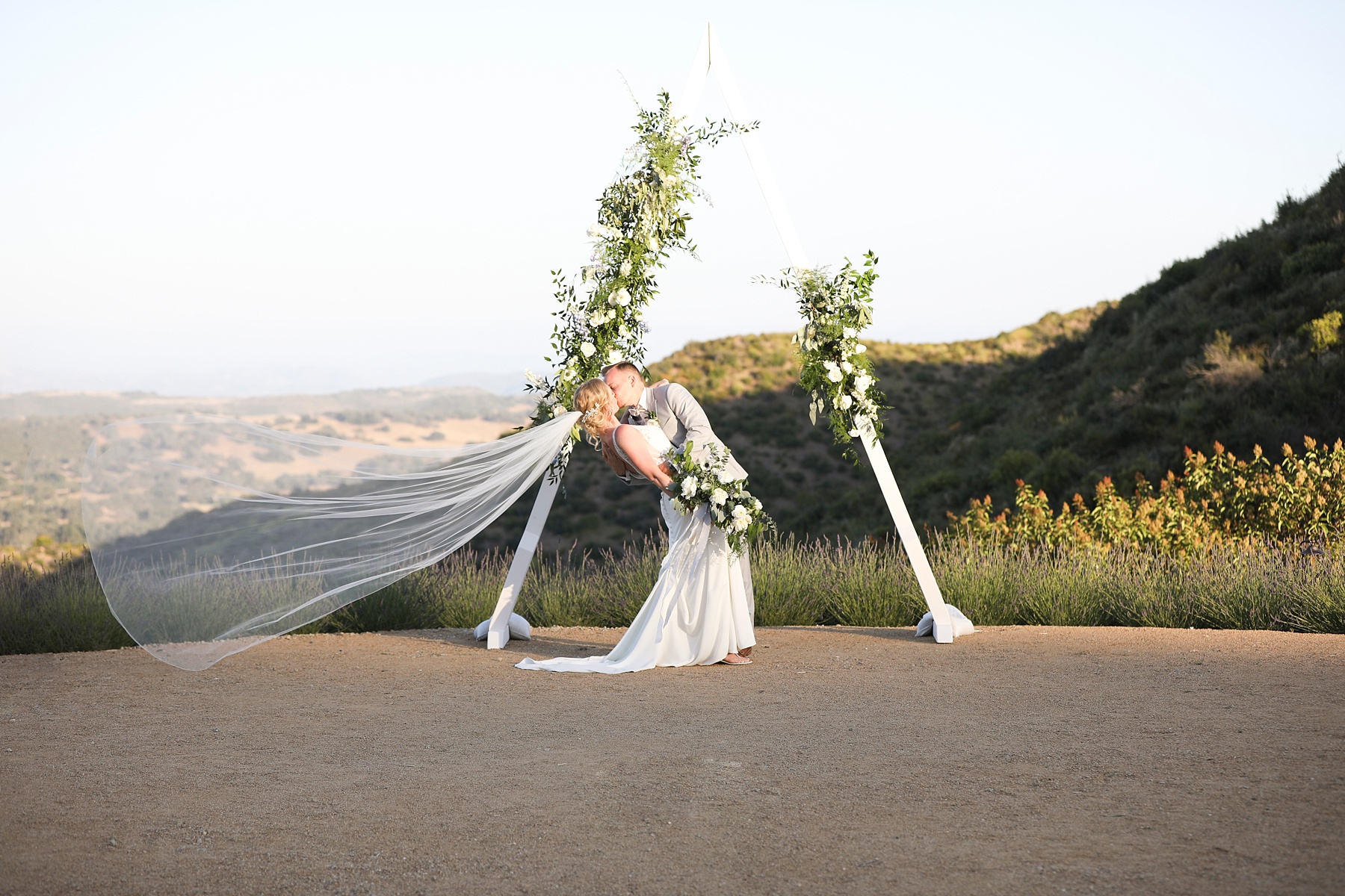 bride and groom kiss in front of triangle modern arbor