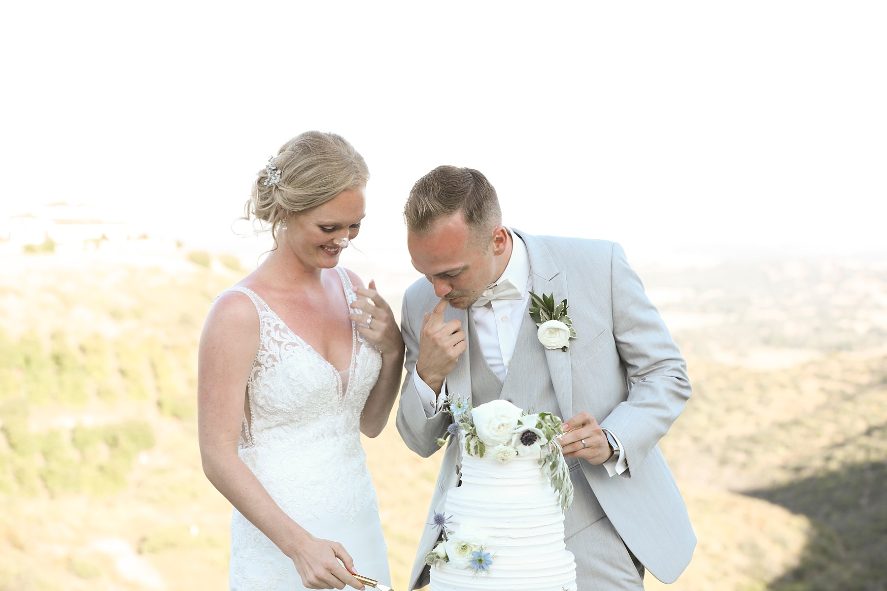 bride and groom laugh with icing on their noses photographed by Randi Michelle Weddings