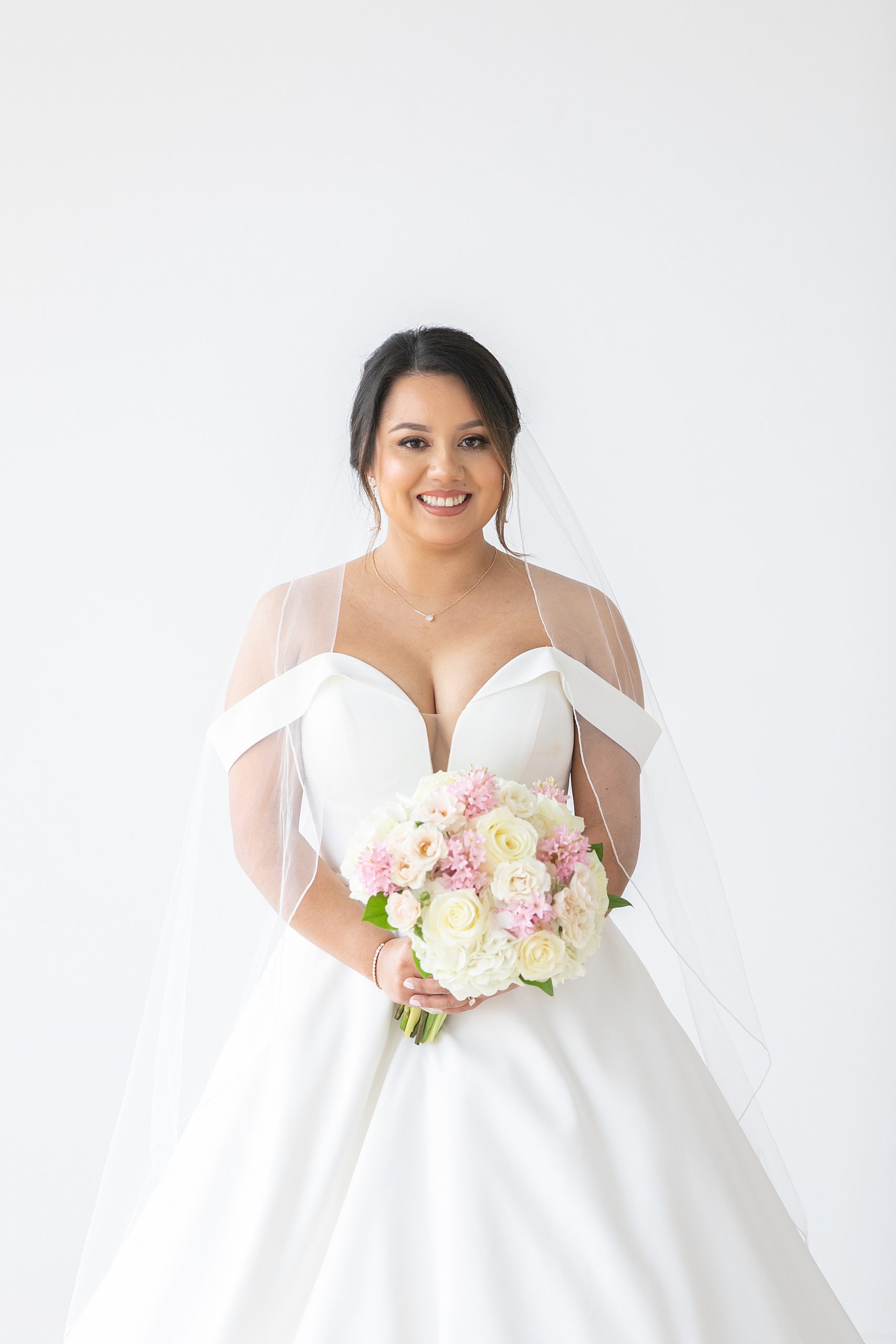 modern Texas bride holds bouquet with veil around shoulders