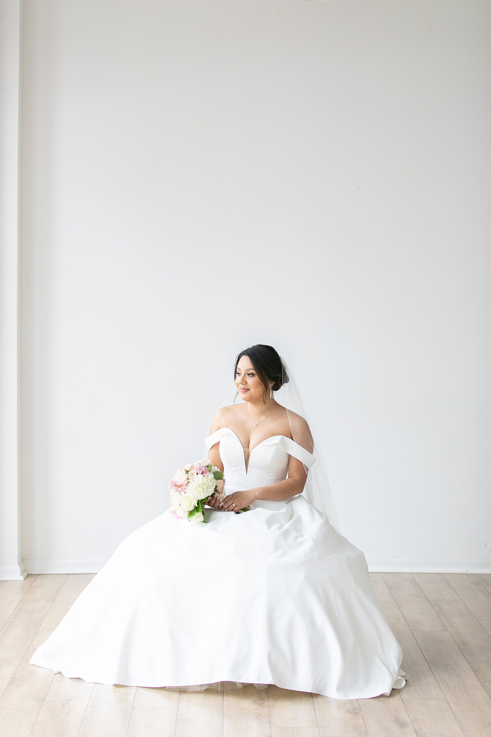 bride sits in chair holding wedding bouquet at Dallas Lumen Room