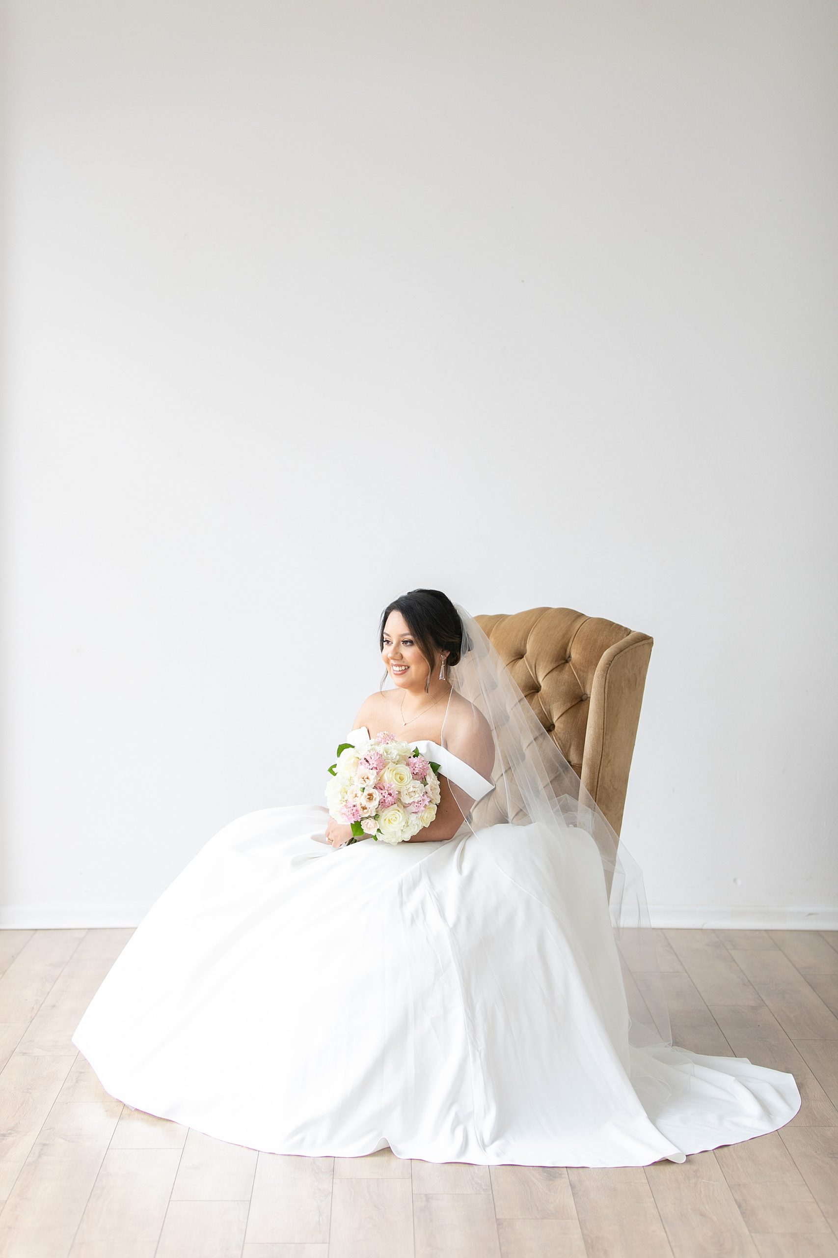 bride sits in gold chair looking out window at Dallas Lumen Room