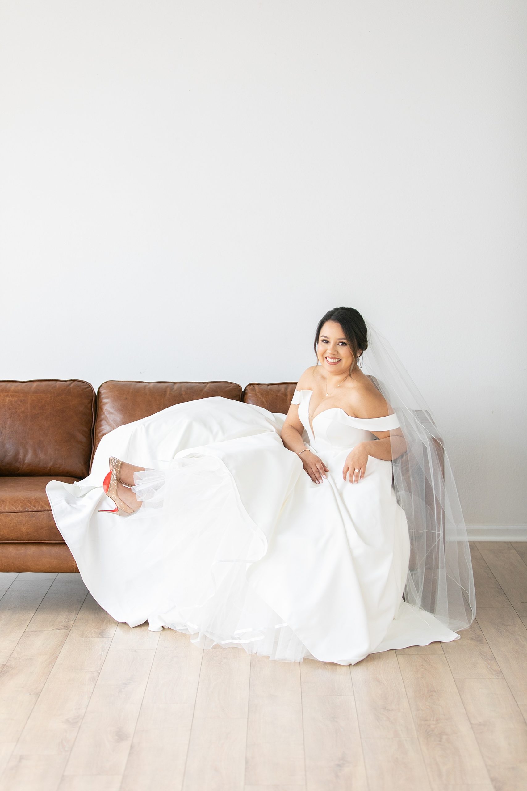 bride sits on chair with feet up and laughs at Dallas Lumen Room