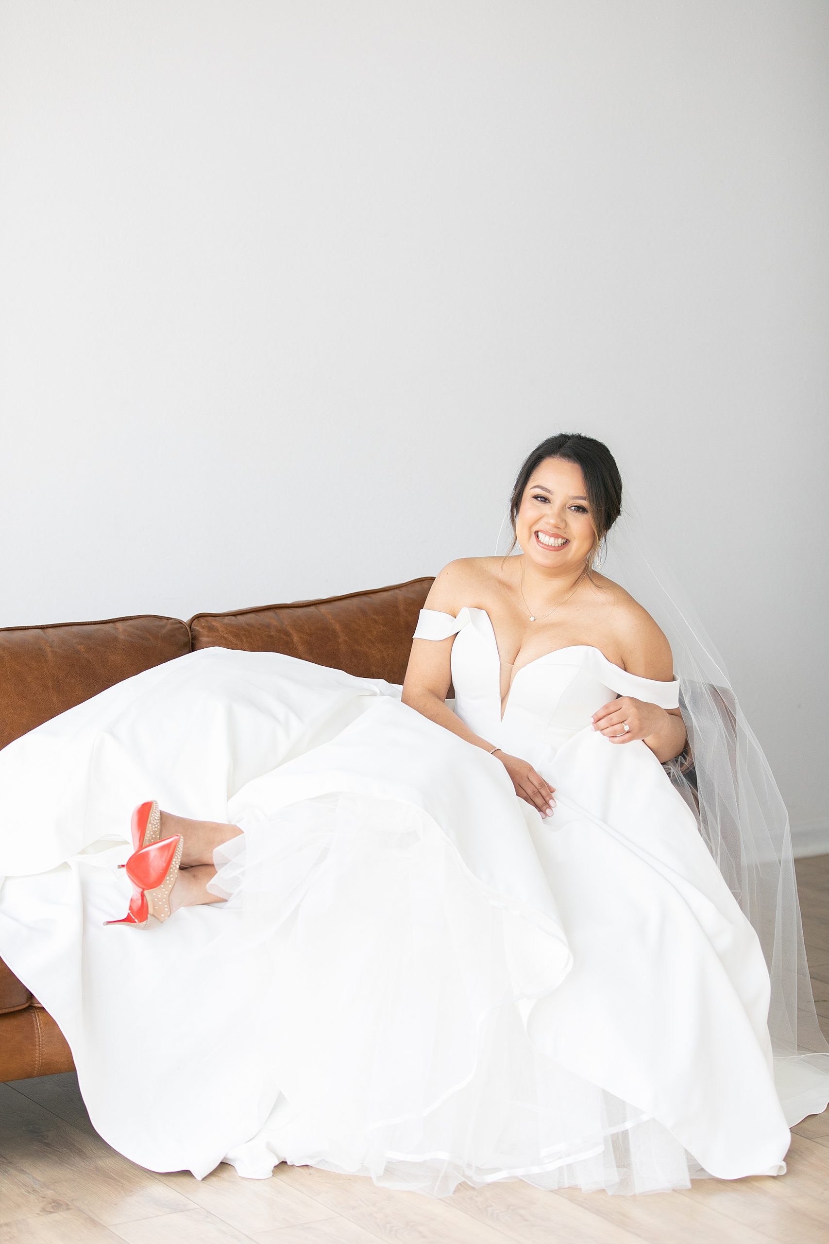 TX bride sits on couch in wedding dress with veil