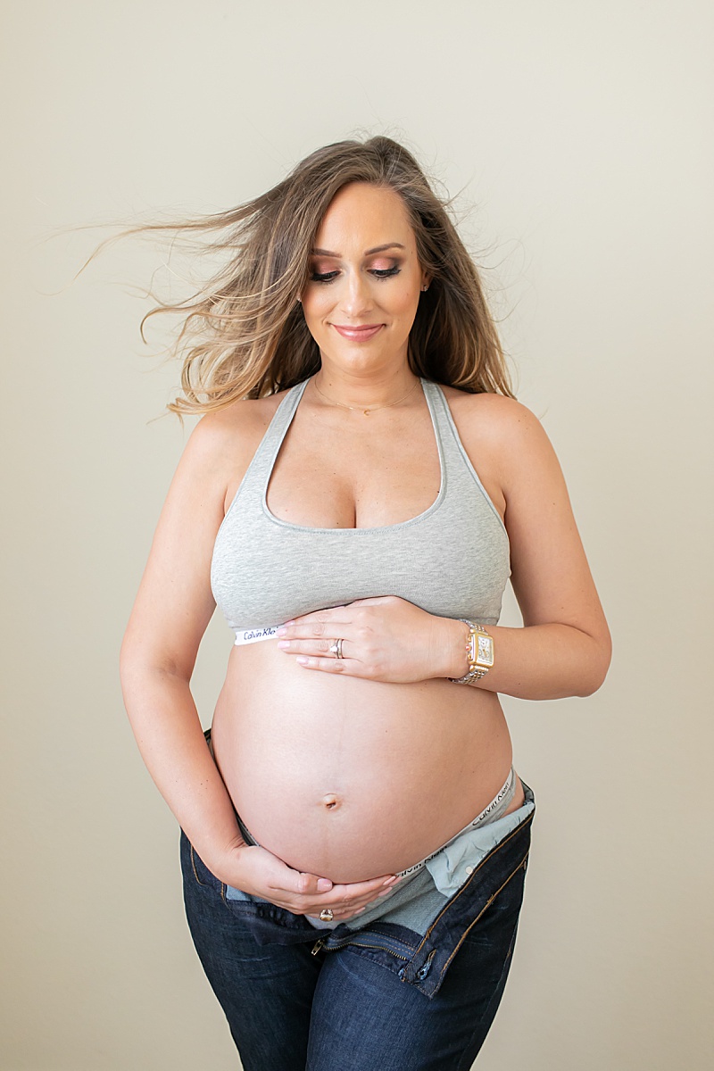 mom holds belly during maternity portraits in Dallas TX