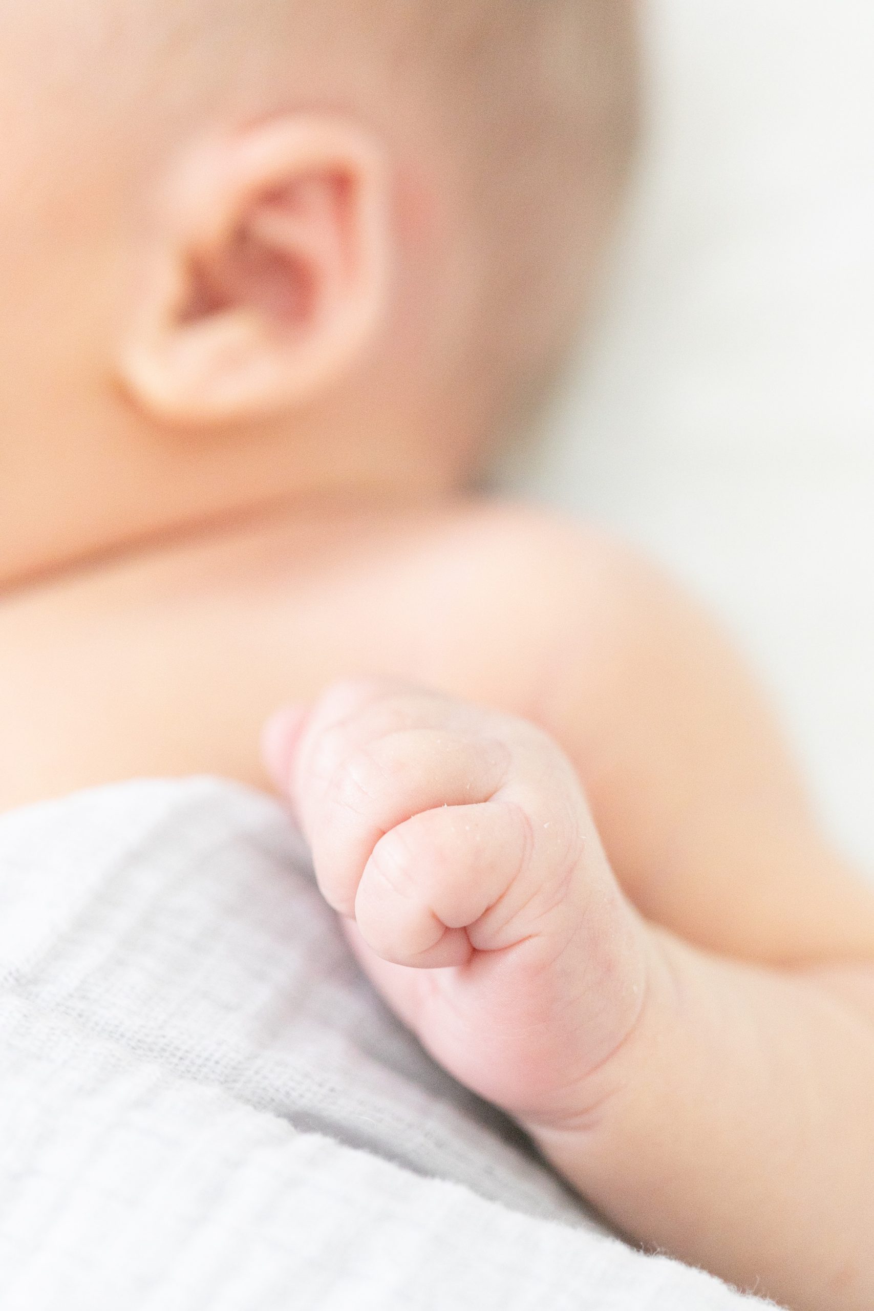baby clenches hand together during newborn session at home