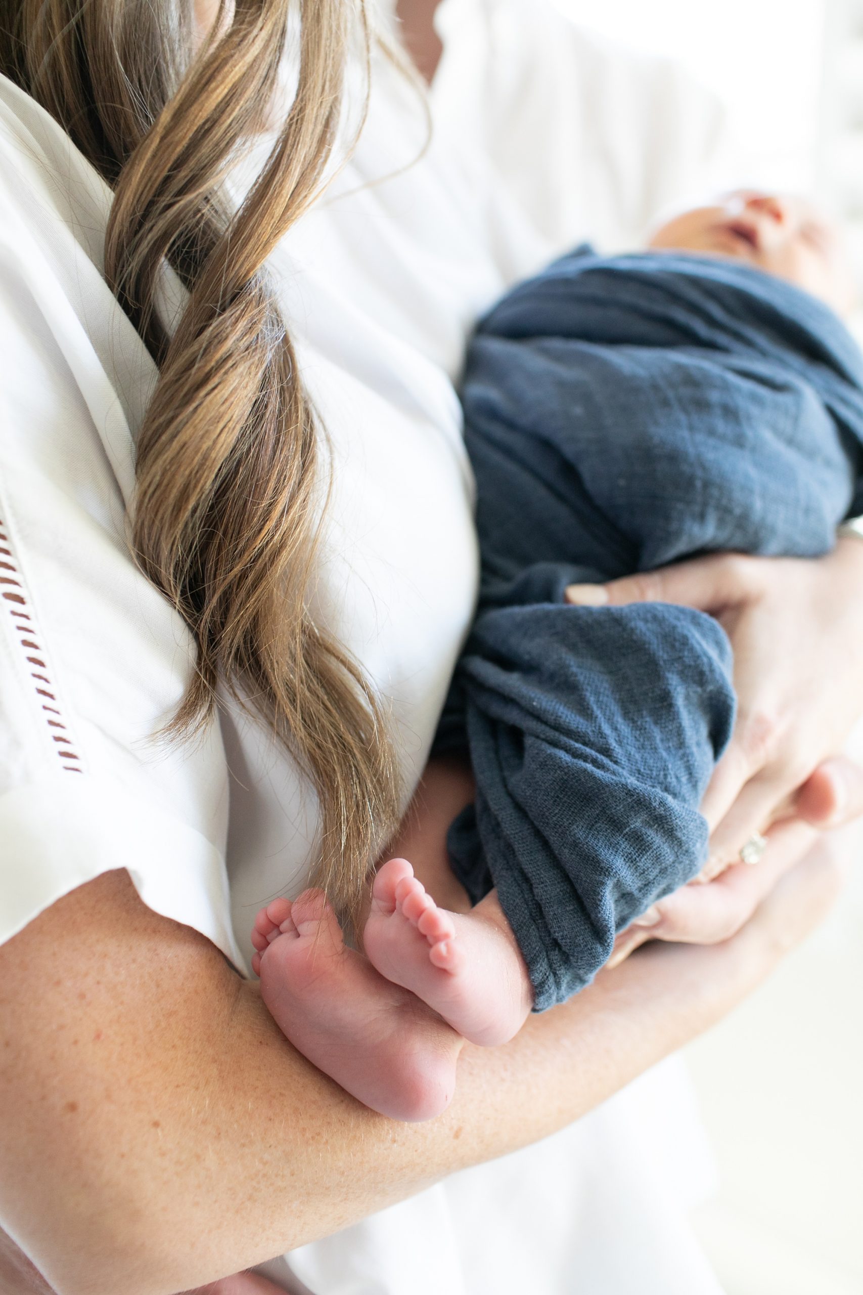 mom holds baby boy while feet stick out of blue wrap