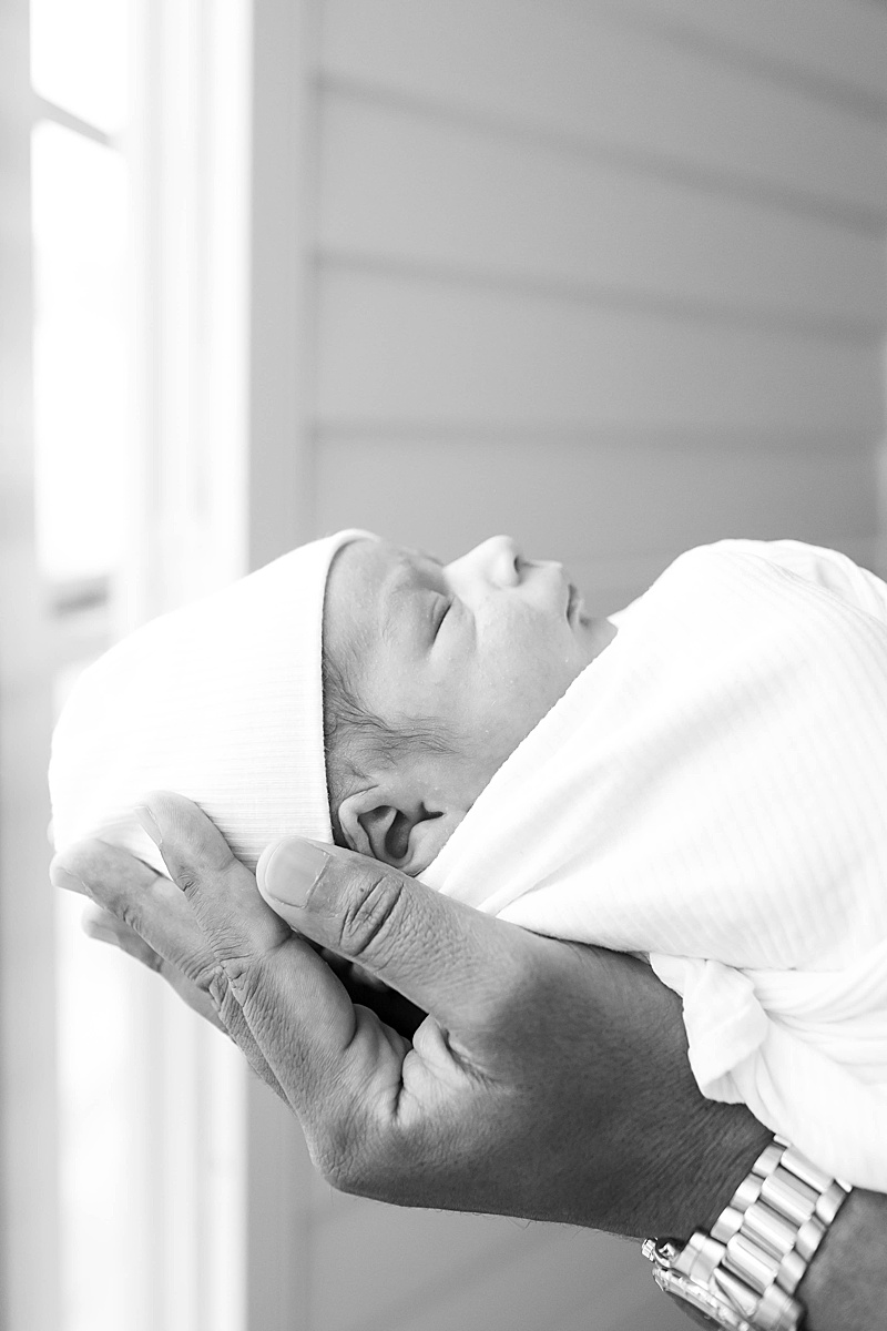 baby boy snuggles in dad's hands during Dallas TX Lifestyle Newborn Session