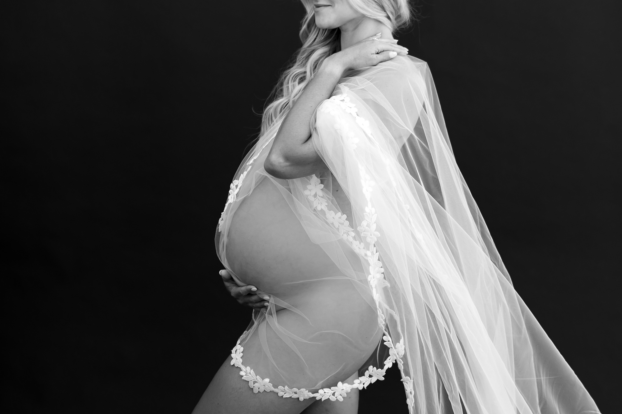 mom holds veil around pregnant belly naked