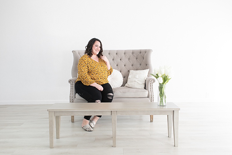 wedding planner sits on grey couch for branding session