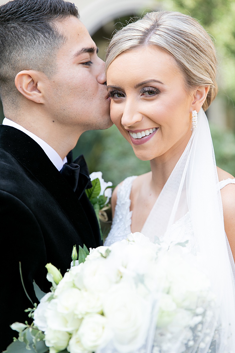 groom kisses bride while she looks at camera at Chapel at Ana Villa