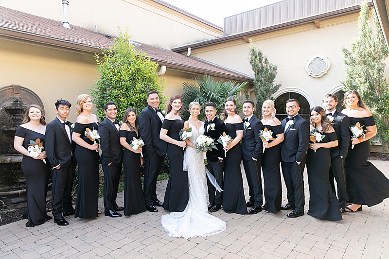 bridal party in all black for winter wedding poses outside Chapel at Ana Villa