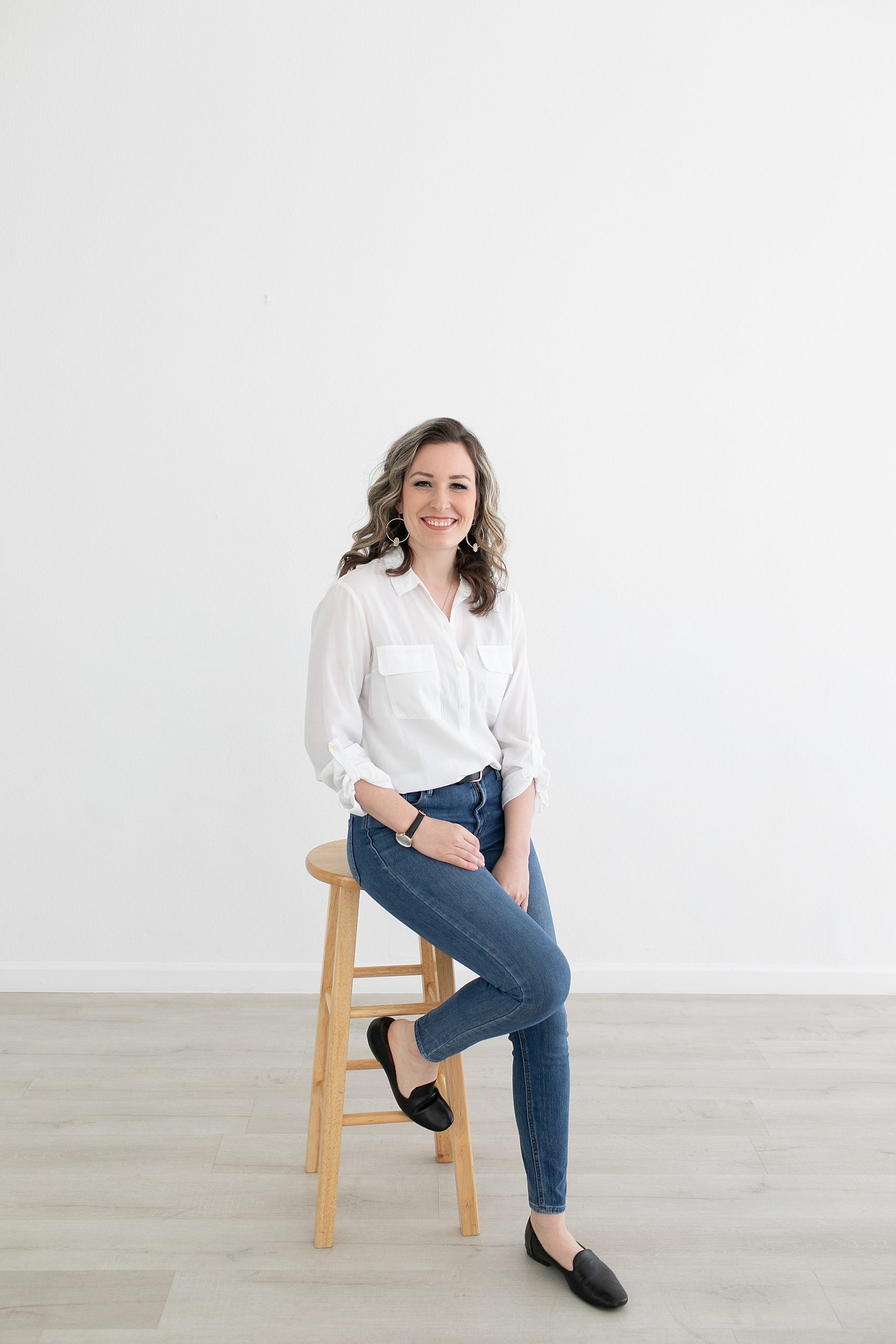 wedding planner sits on stool in white shirt and jeans