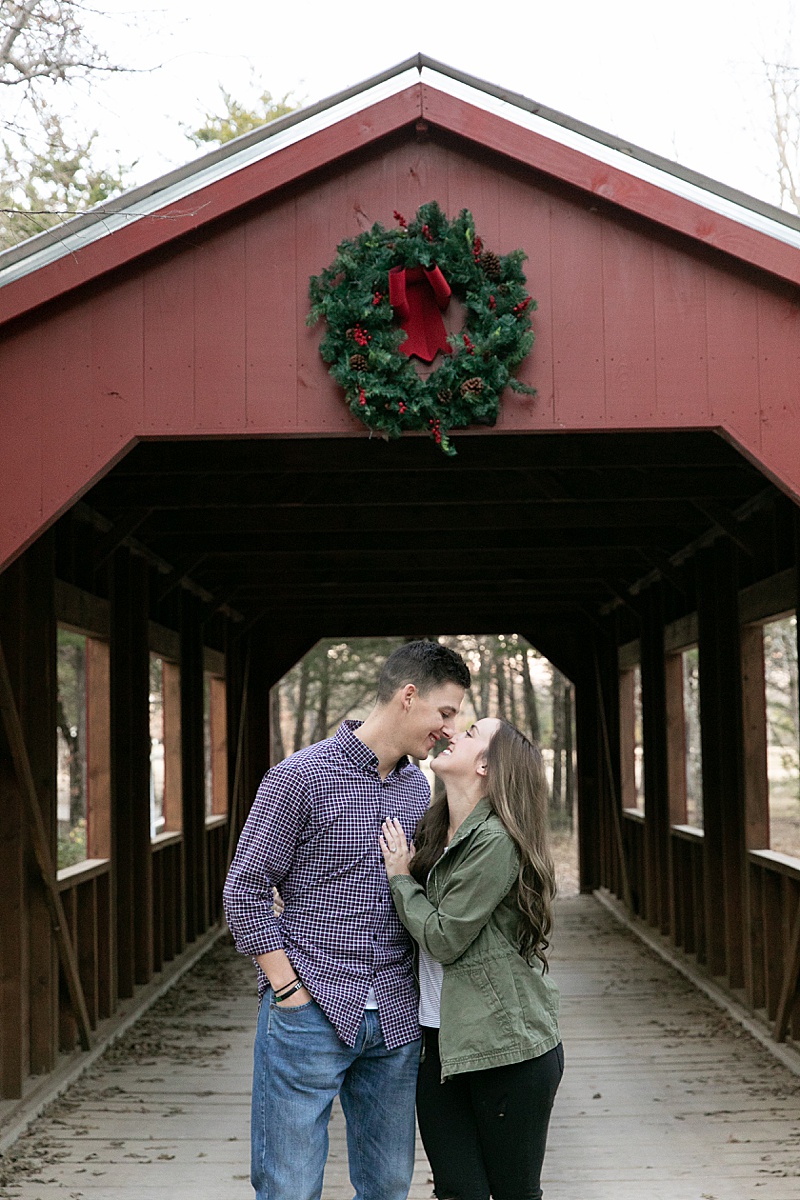 recently engaged couple poses by covered bridge at the French Farmhouse