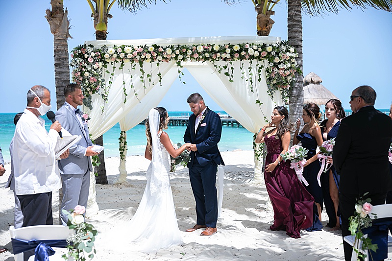 bride and groom exchange vows on beach