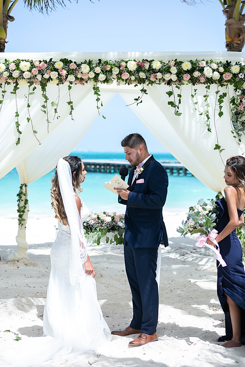 groom reads bride vows during beach wedding