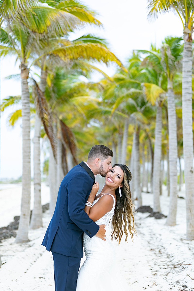 bride and groom embrace under palm trees