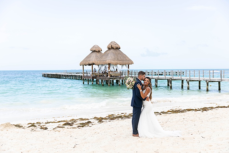 wedding portraits with cabana and blue ocean behind bride and groom