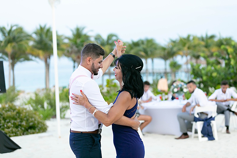 groom and mom of bride dance on beach