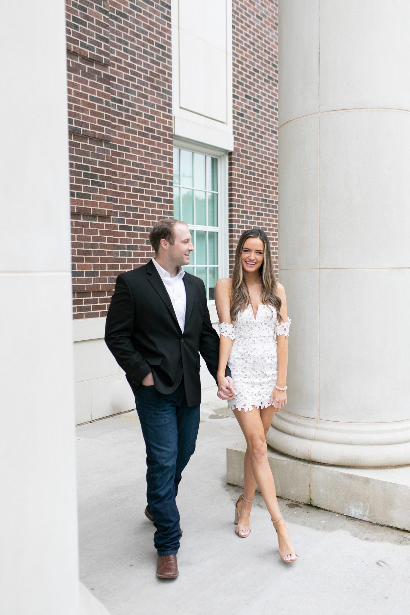 engaged couple holds hands walking through SMU Dallas