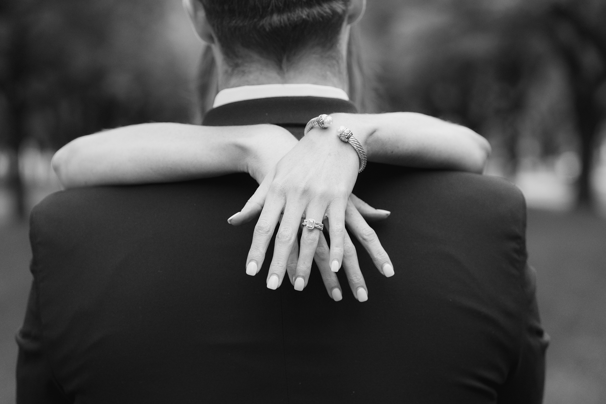 engagement ring on bride's hand around groom's neck