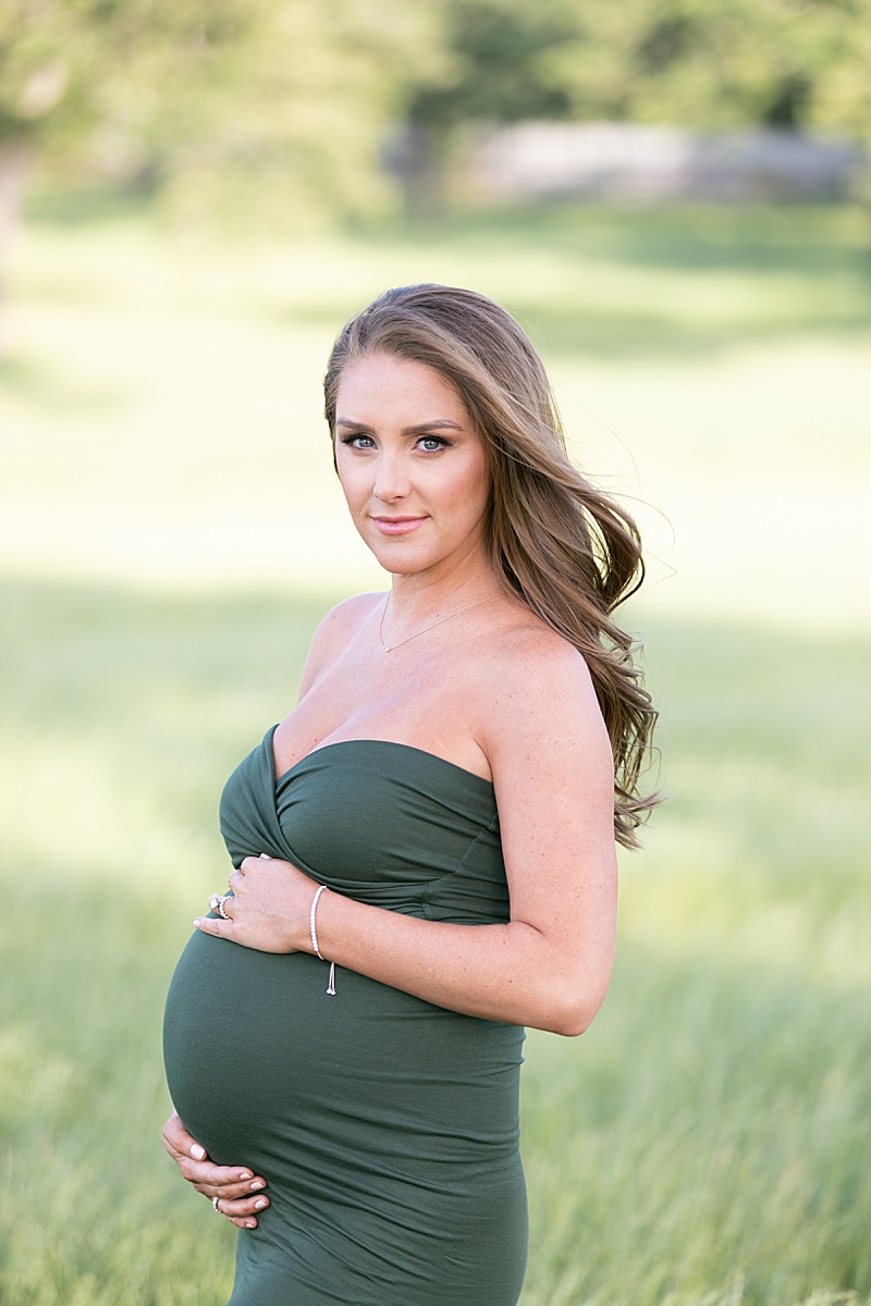 mom holds baby belly in green gown