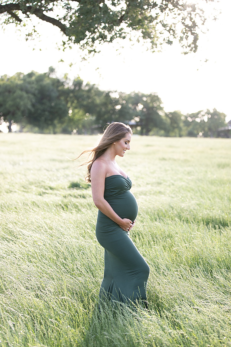 mom looks down at belly during Texas maternity session