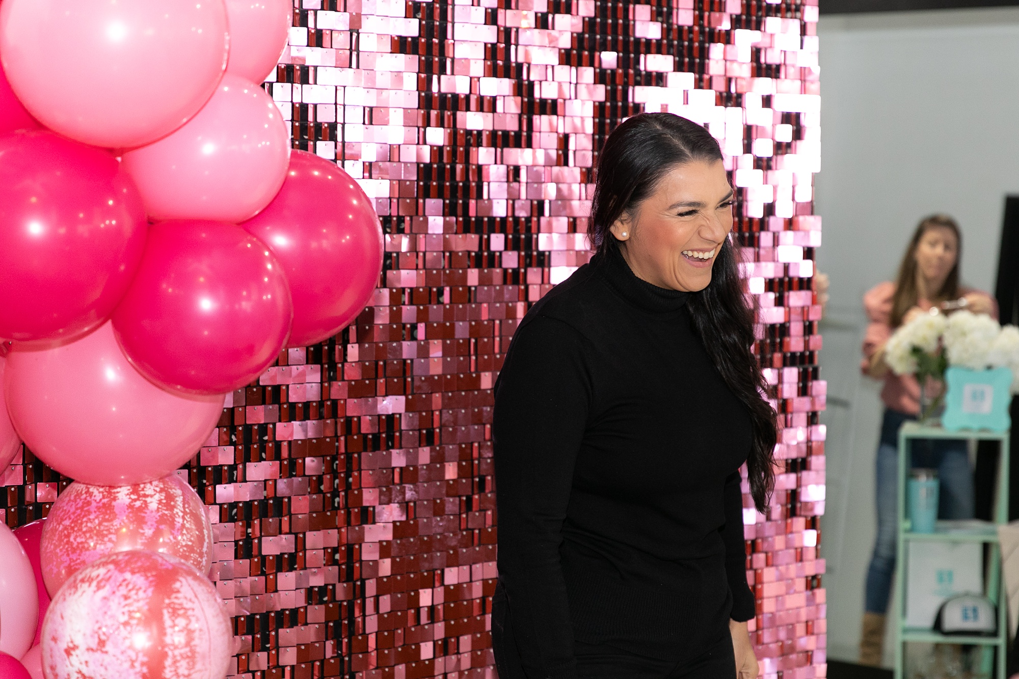 guest laughs in front of hot pink photo booth backdrop