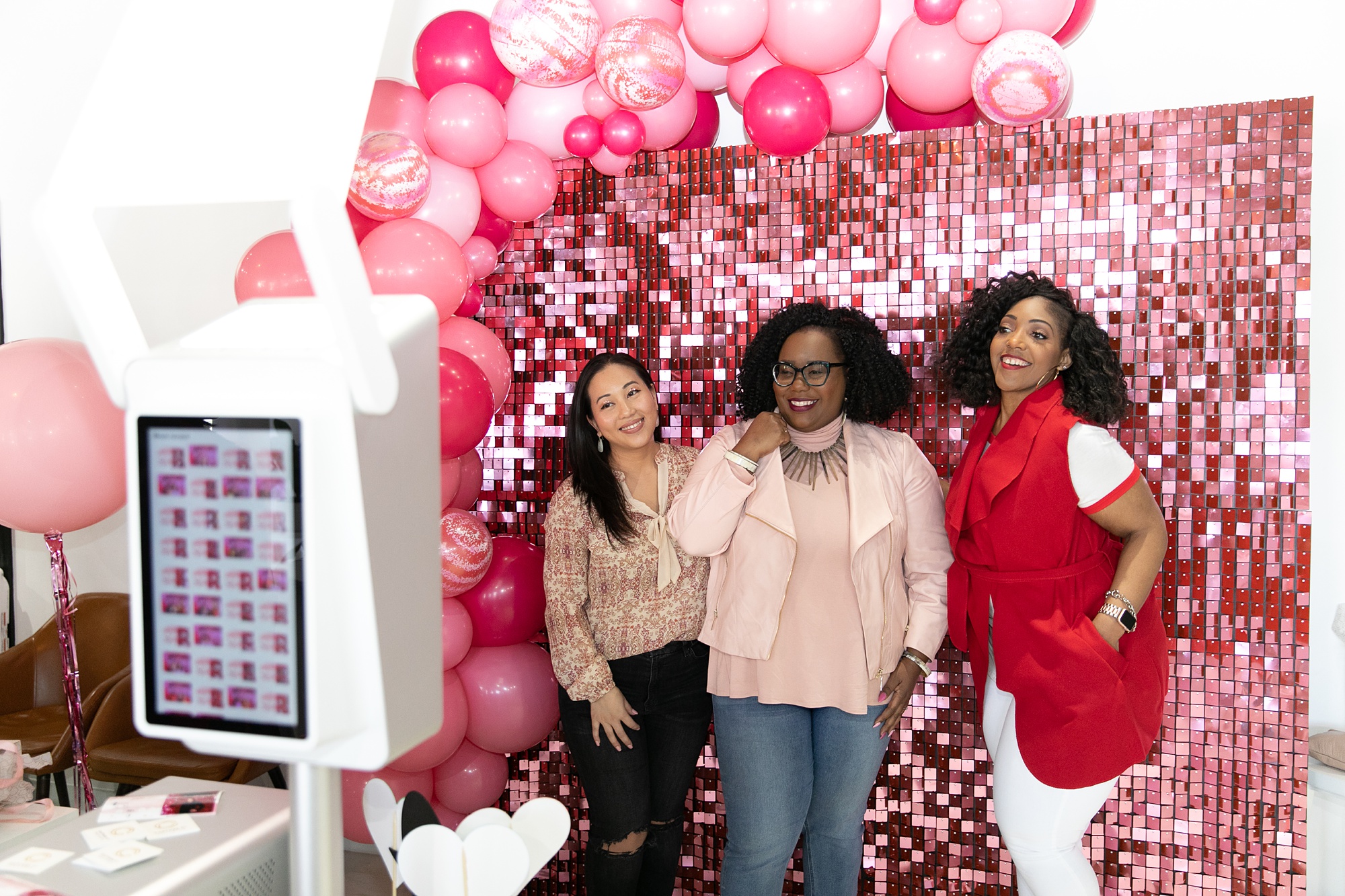 women pose in photobooth with pink backdrop and balloons at Dallas Girl Gang event