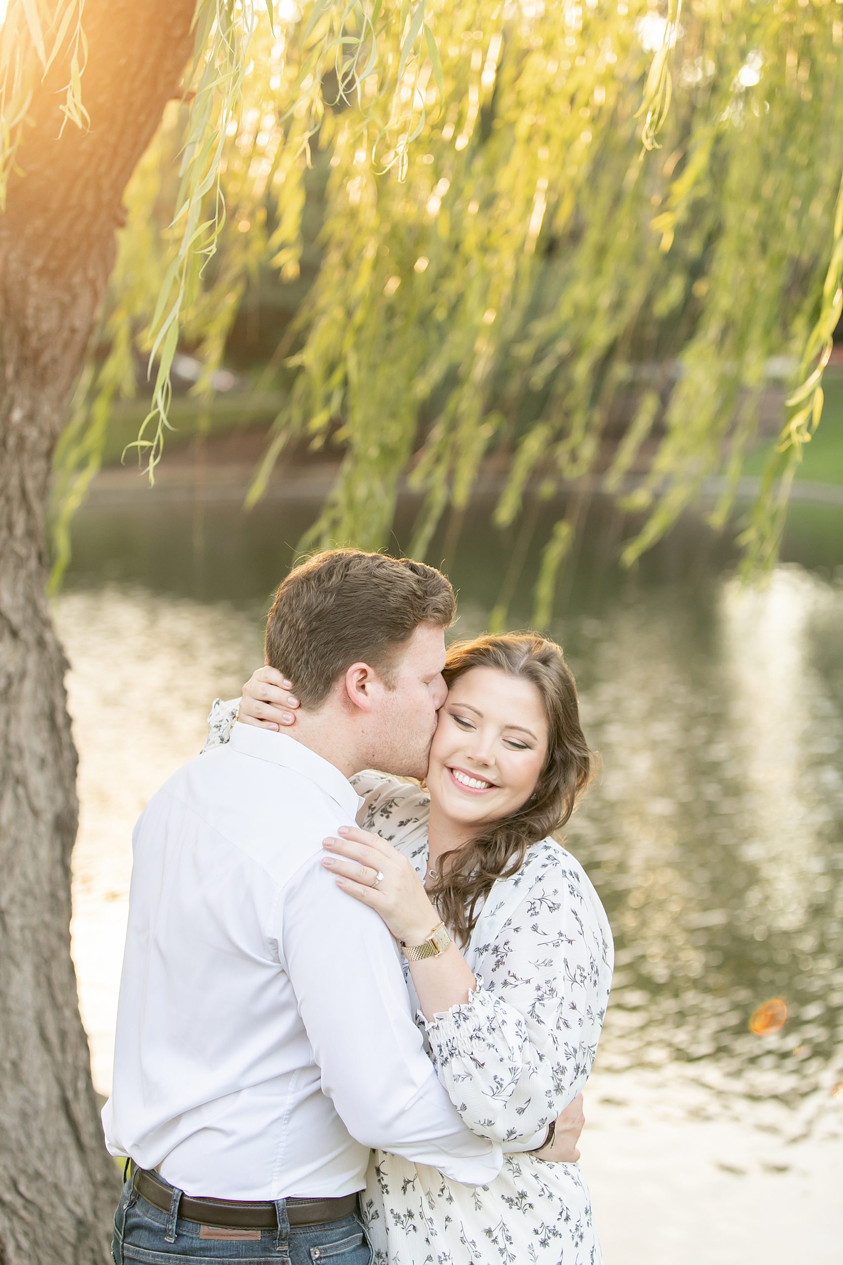 groom kisses bride under willow tree at sunset during Texas engagement session