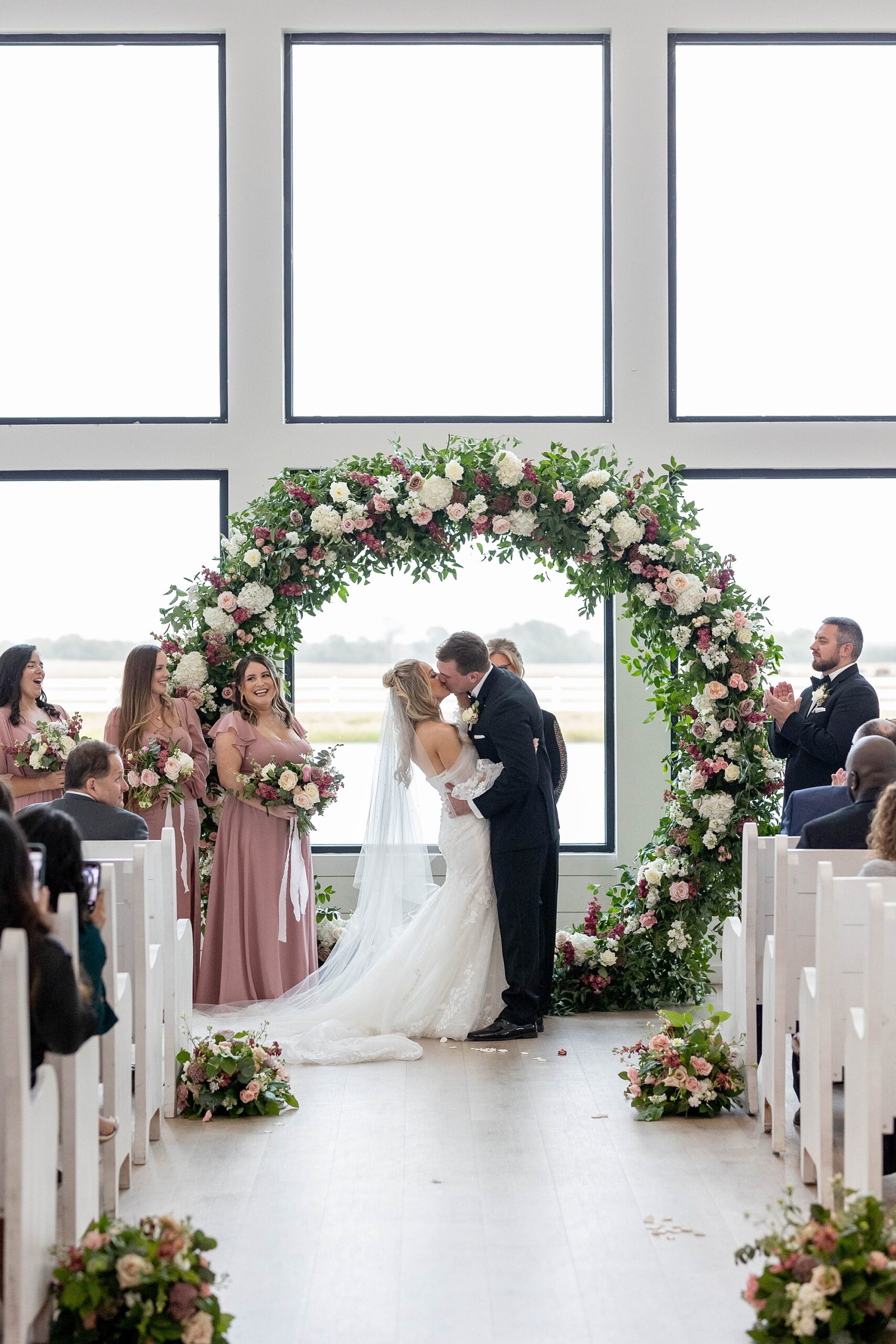 bride and groom kiss under floral arch inside the Gardenia