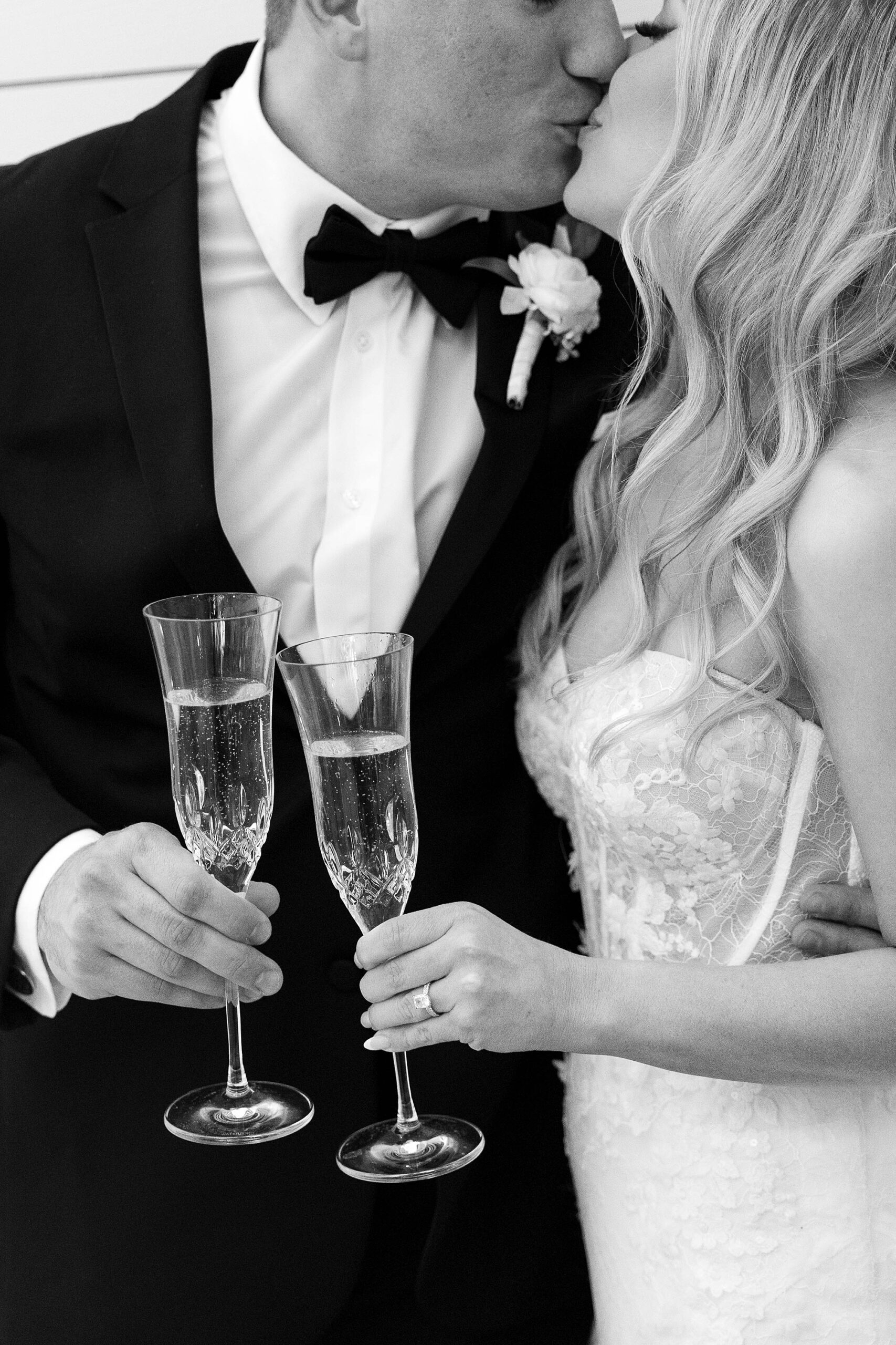 bride and groom kiss holding glasses of champagne at the Gardenia