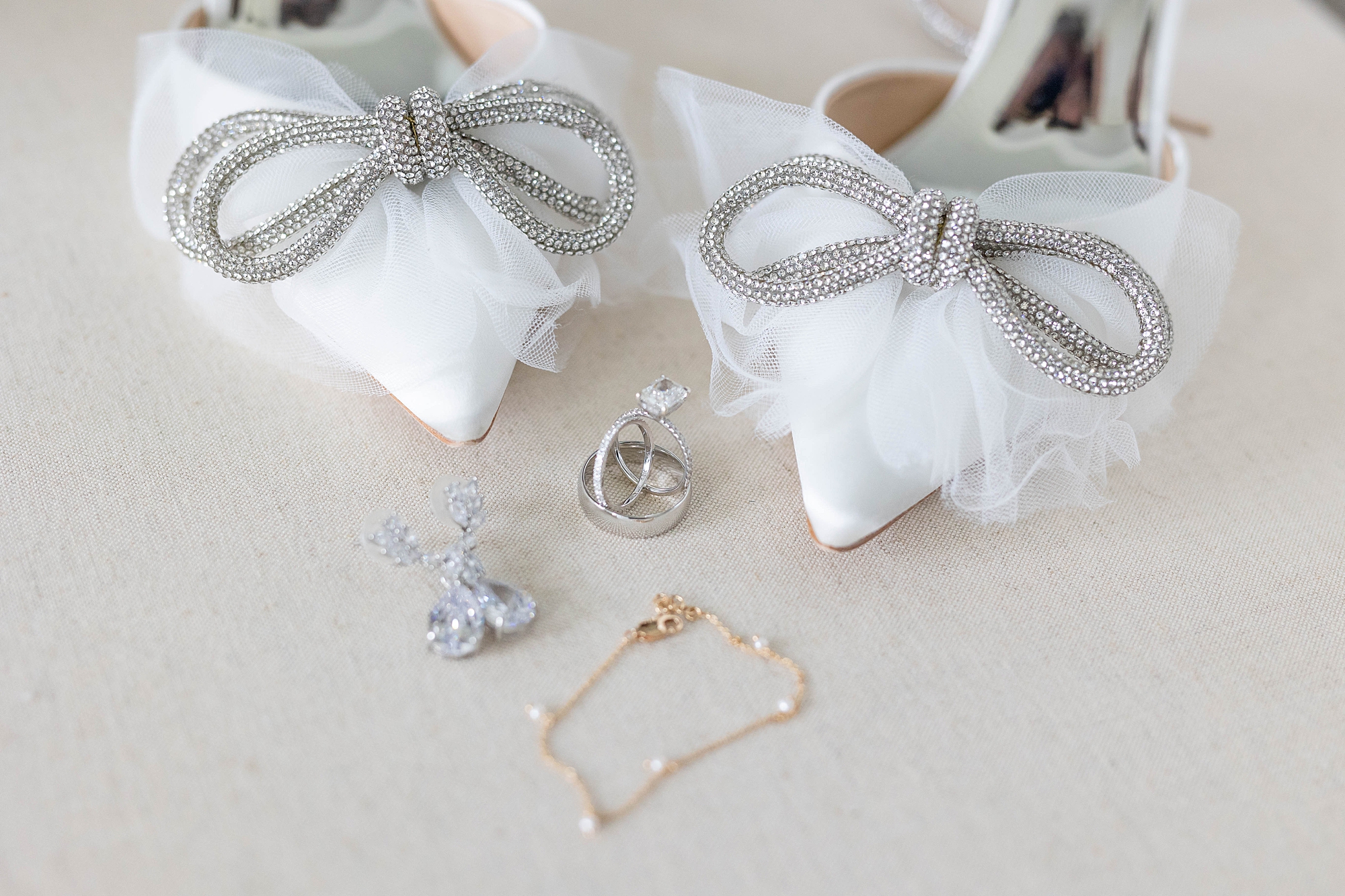 bride's jewelry and white shoes with silver bows