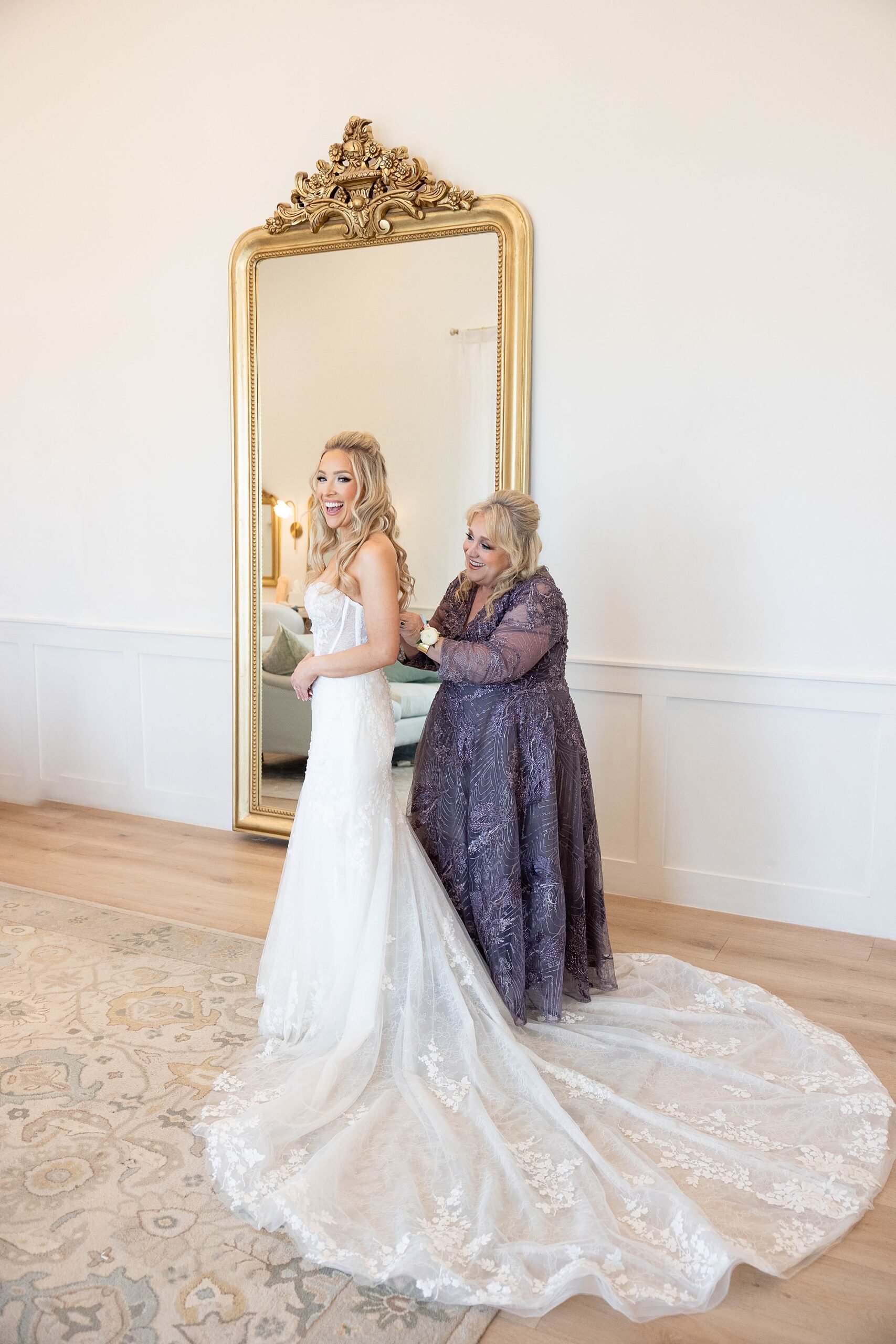 mother helps bride into wedding dress during prep at the Gardenia