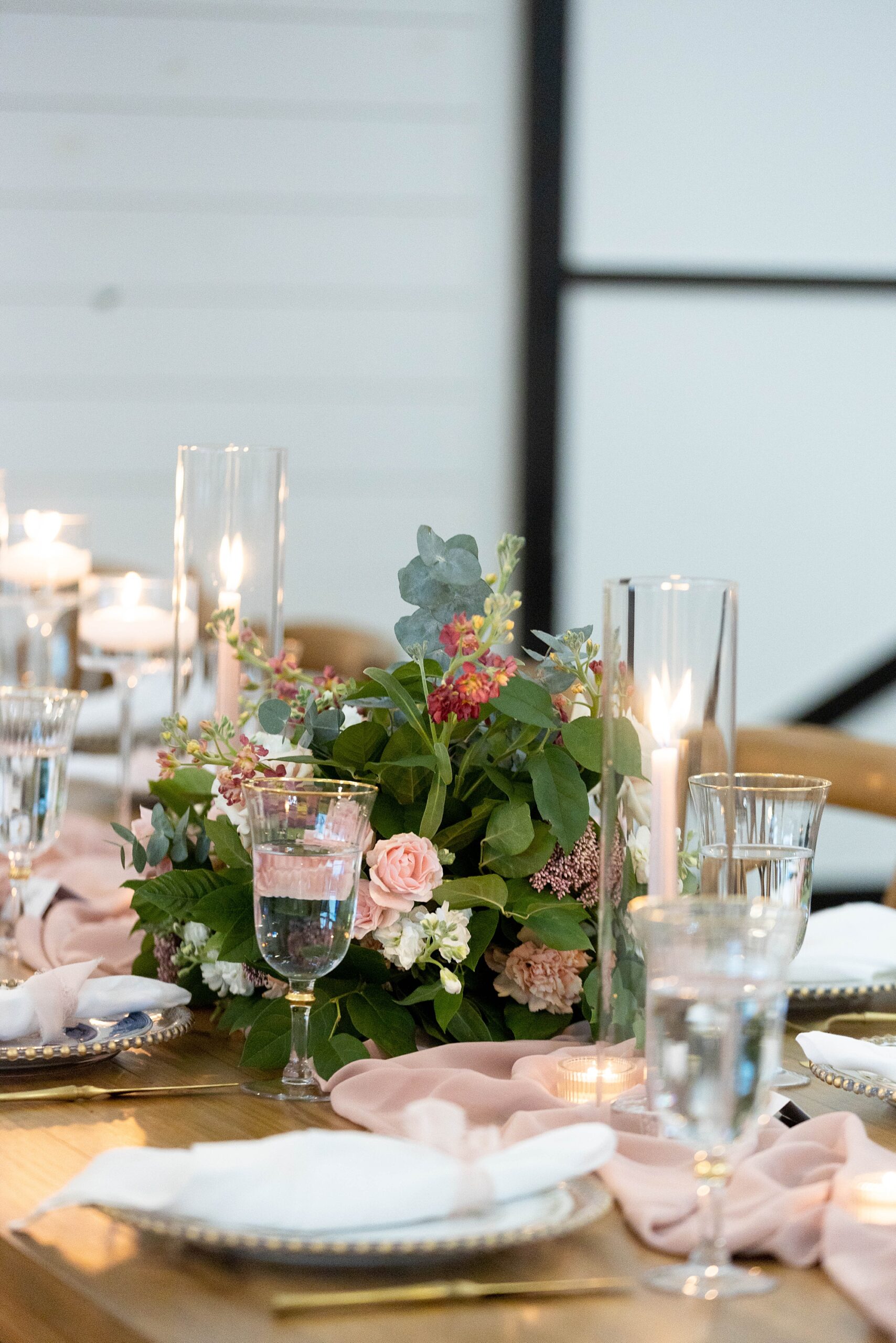 fall wedding reception decor with pink flowers, taper candles, and gold place settings at the Gardenia