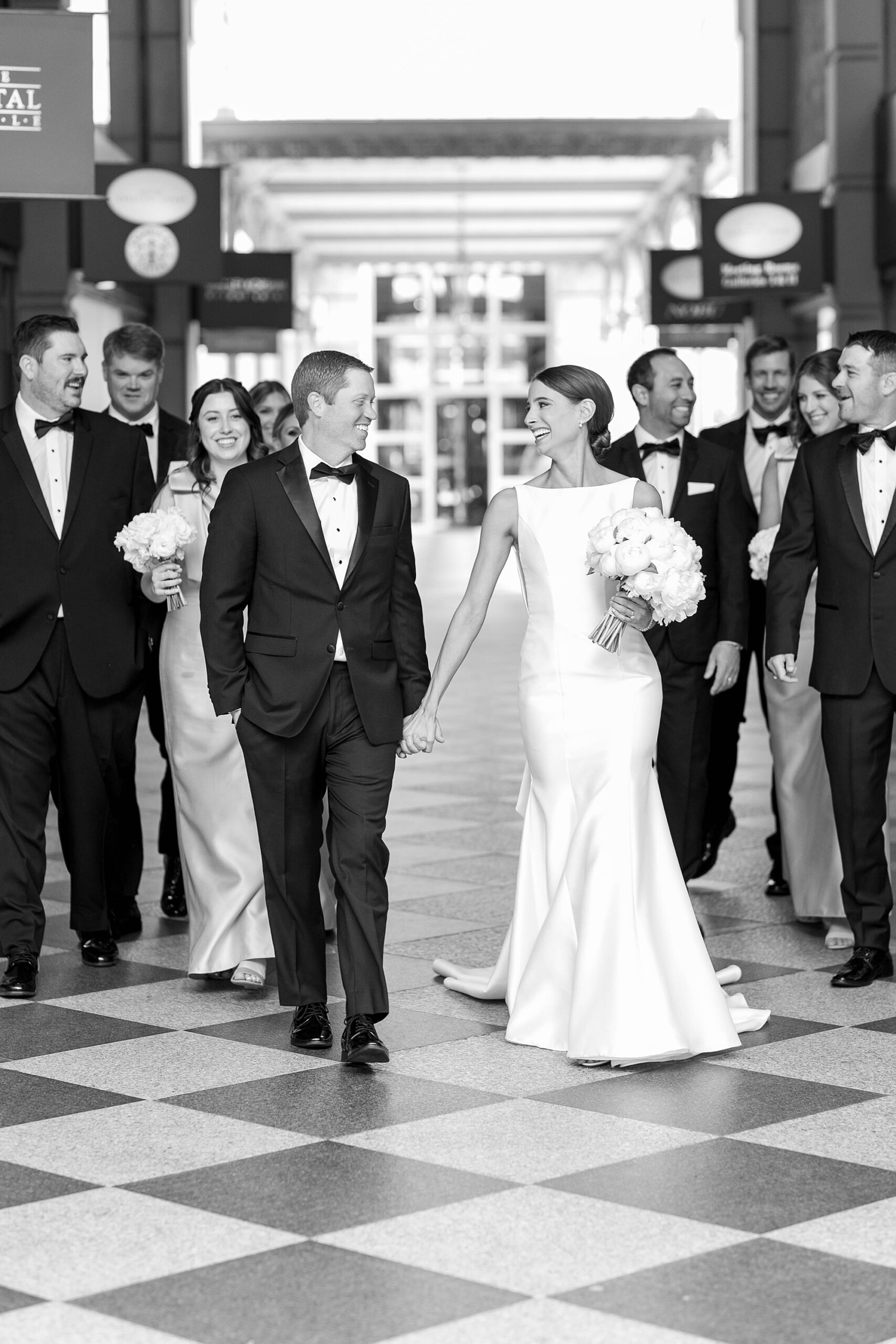 bride and groom hold hands walking between wedding party outside the Hotel Crescent Court