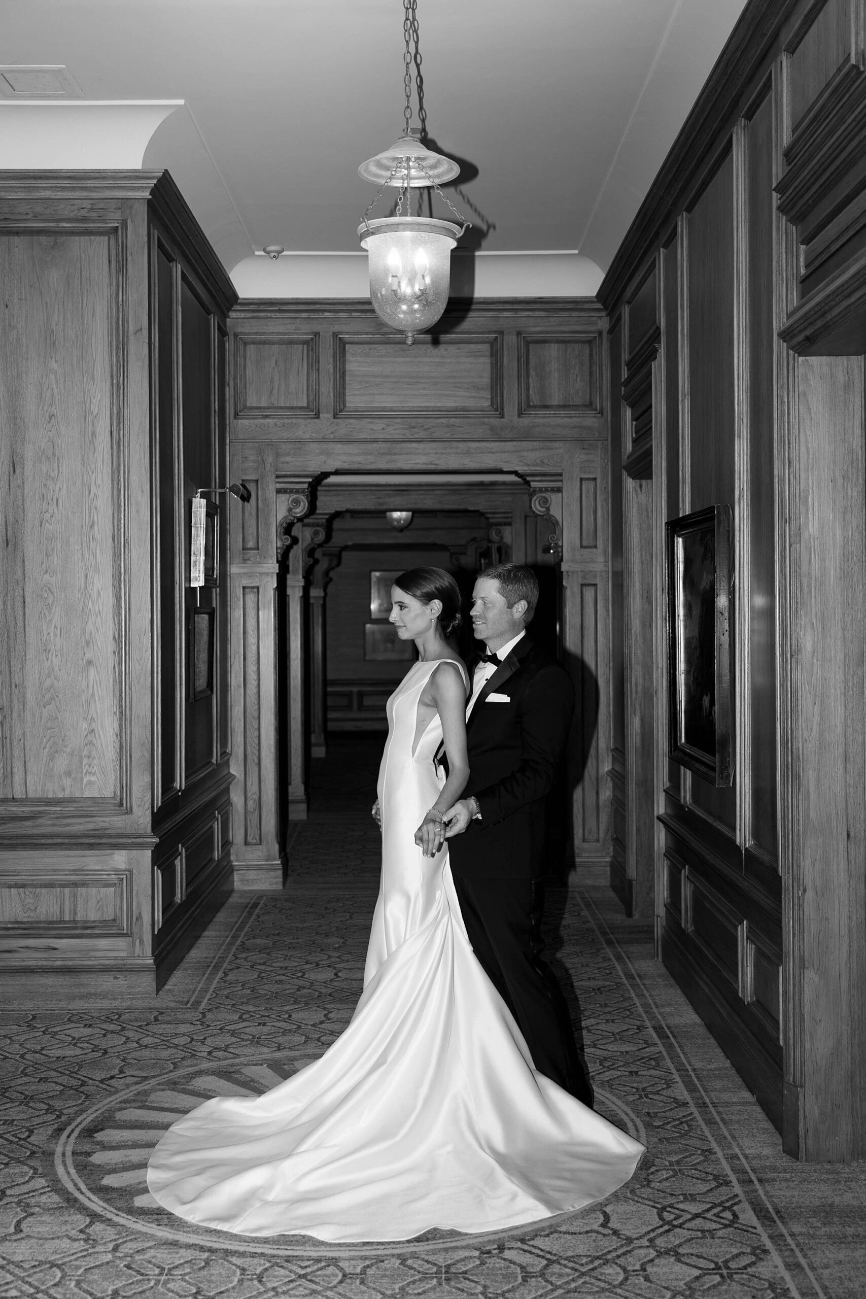 groom stands behind bride in hallway hugging her at the Hotel Crescent Court