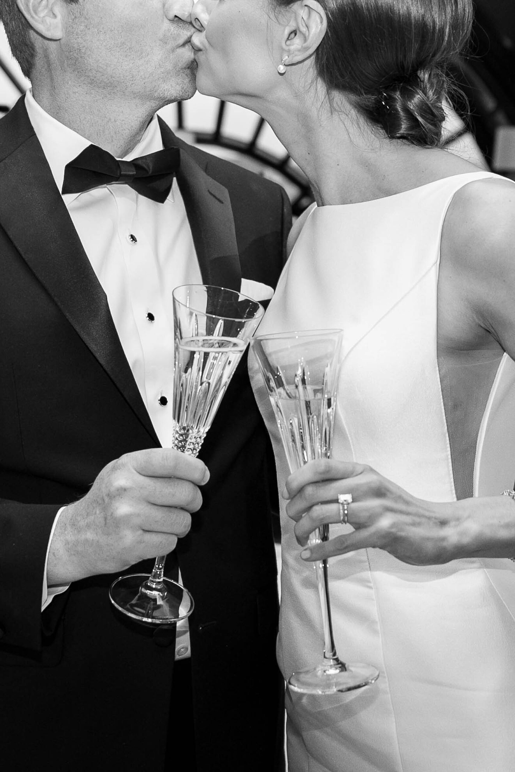 newlyweds toast champagne glasses while kissing at the Hotel Crescent Court