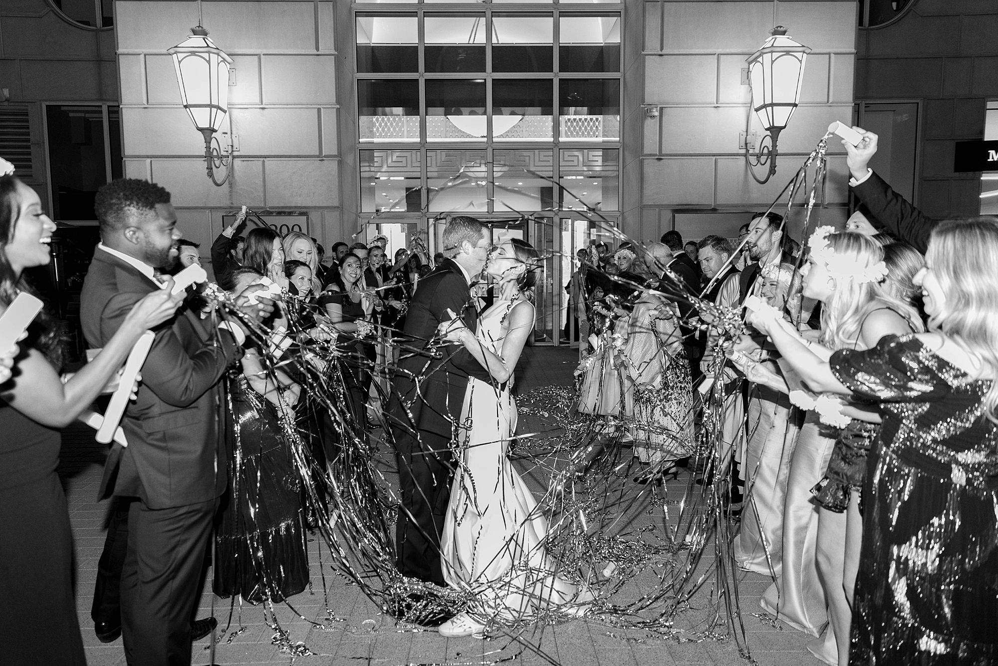 bride and groom kiss leaving wedding reception through streamer exit