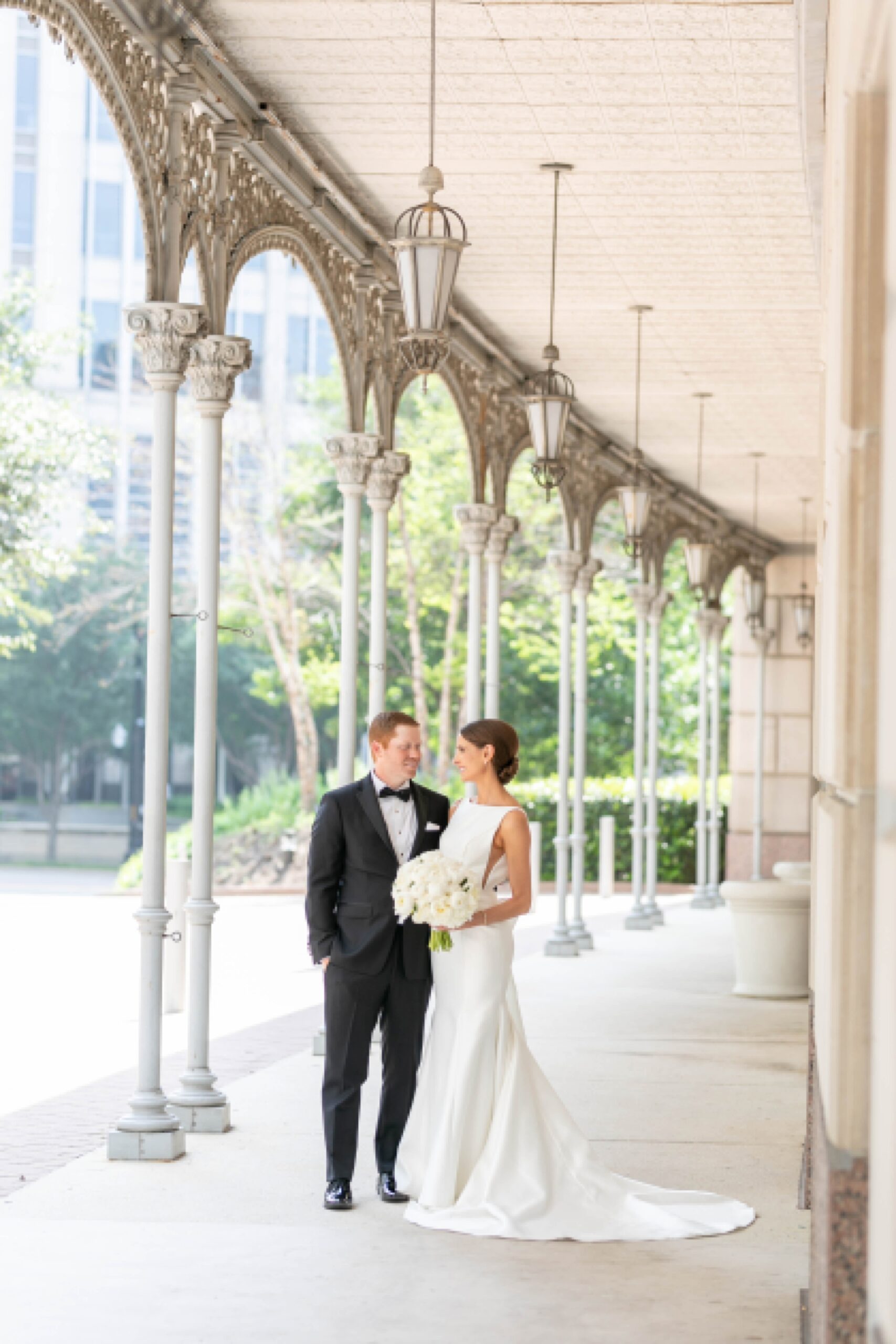 bride and groom hug under walkway with arches at the Hotel Crescent Court